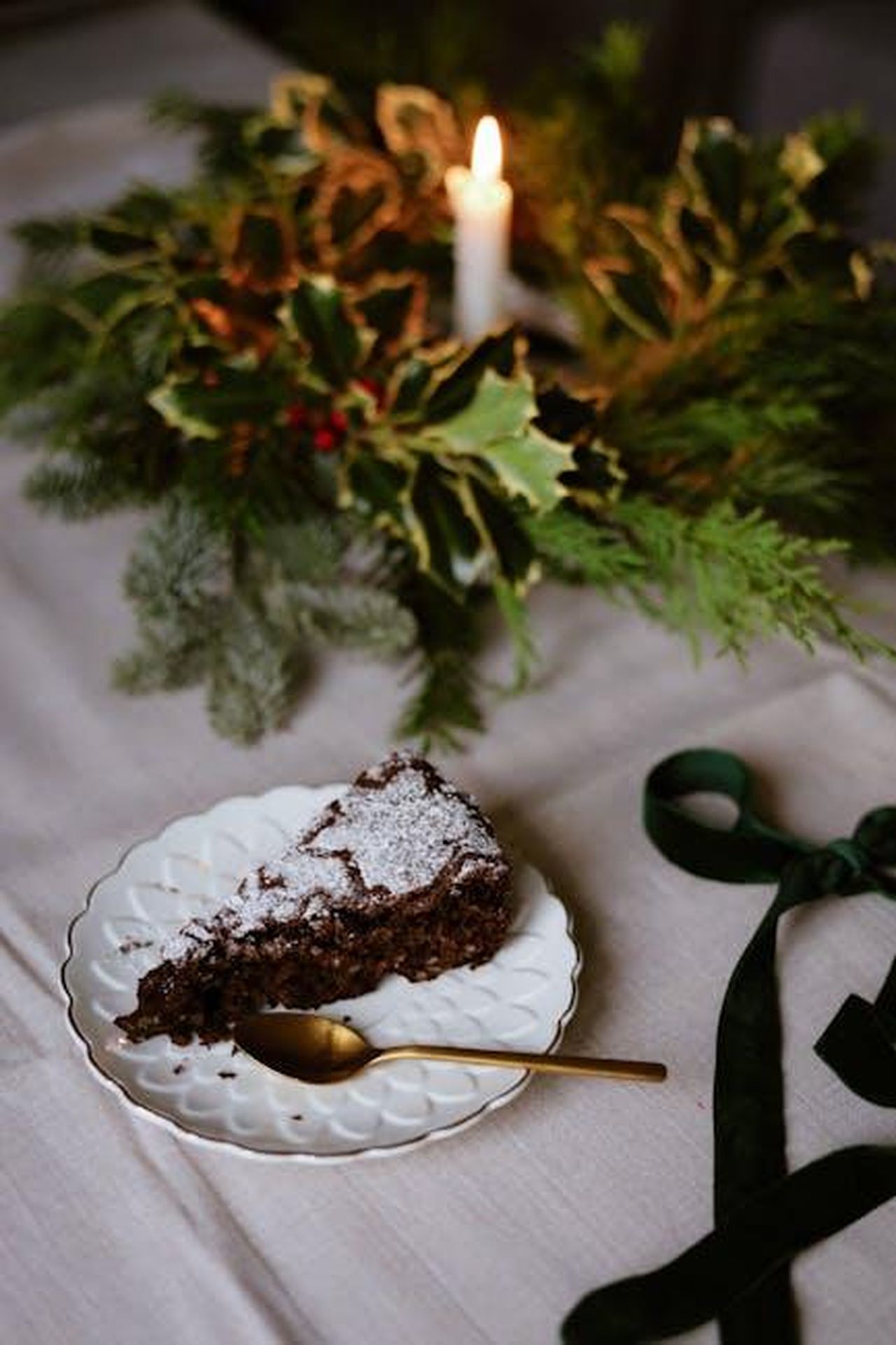 Passare_oltre_ITV_El9Dec5NTk - Confidenze24 Source: Nati - pexels - A piece of chocolate cake on a festive holiday table with greenery and candlelight.