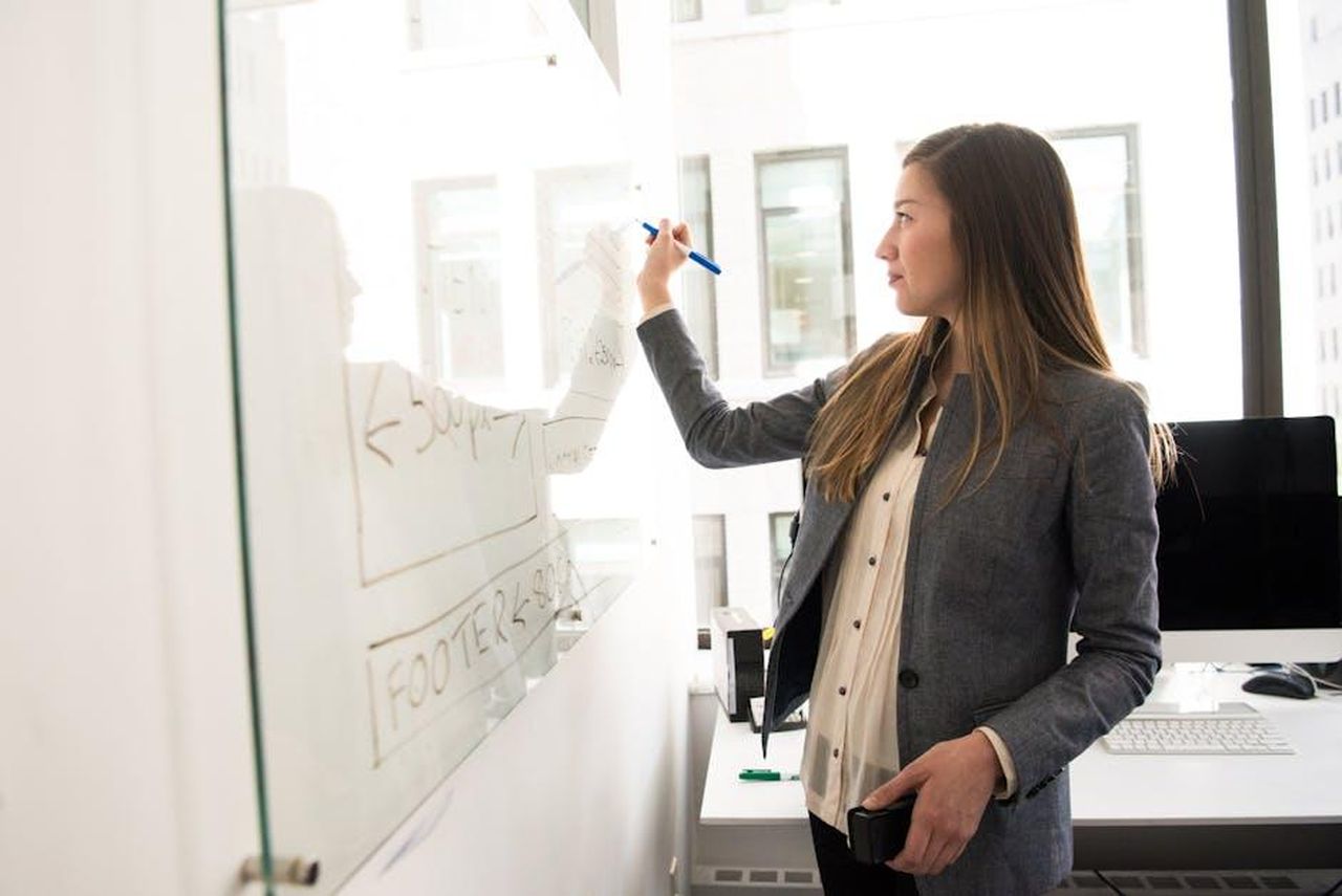 Perch_Harry_non__coinvolto_nei_progetti_di_Meghan_zcOpUxiTxN - Confidenze24 Source: Christina Morillo - pexels - Professional woman writing on a whiteboard in an office environment, focusing on ideas.