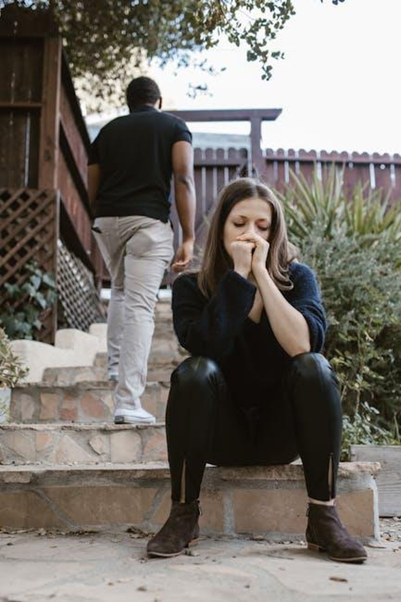 Perch_James_Haskell_e_Chloe_Madeley_si_sono_separati_EpzFcqrAOT - Confidenze24 Source: RDNE Stock project - pexels - A woman sitting in distress while a man walks away outdoors, capturing emotion and separation.
