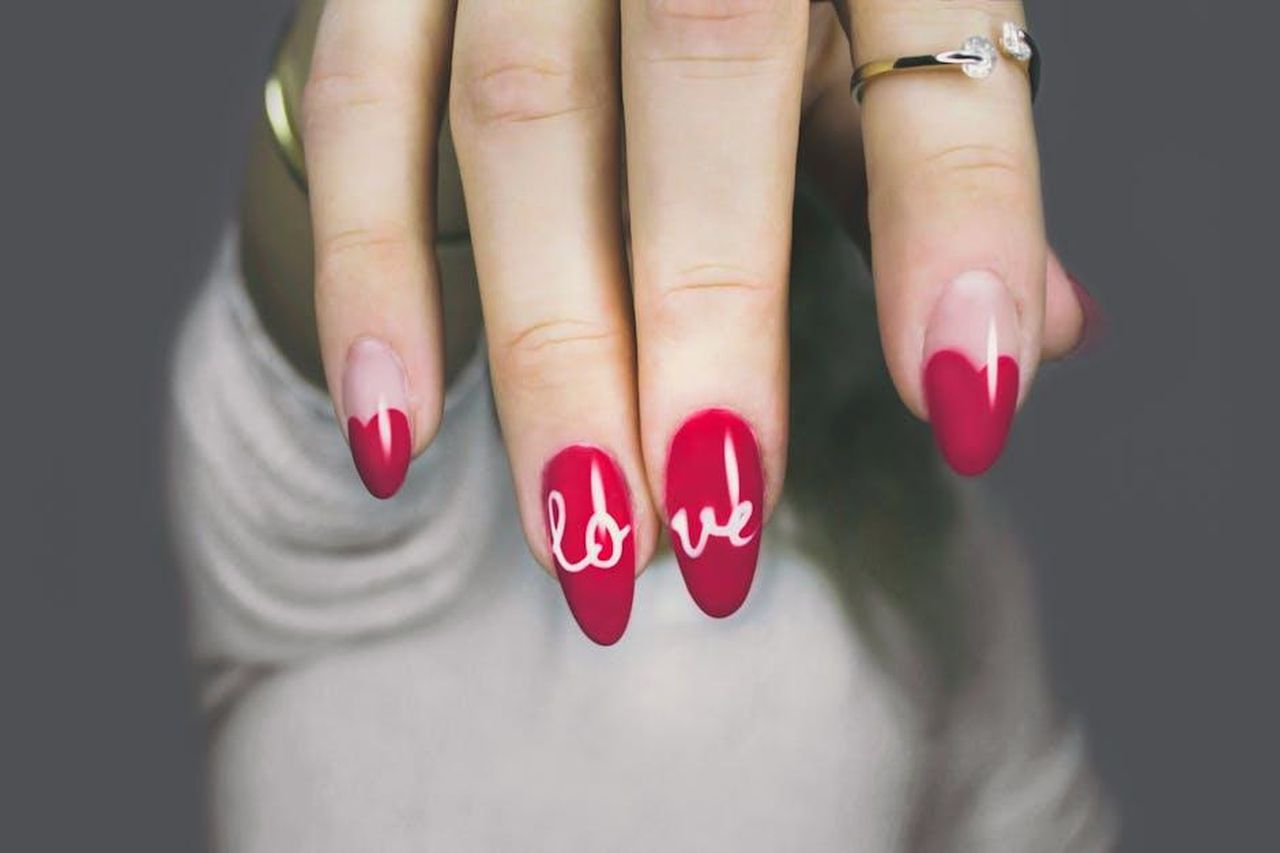 Perch_gli_adolescenti_vogliono_limiti_di_et_7iWdVwA6WH - Confidenze24 Source: Designecologist - pexels - Vibrant red nails with 'love' art on a woman's hand, showcasing elegant style and design.