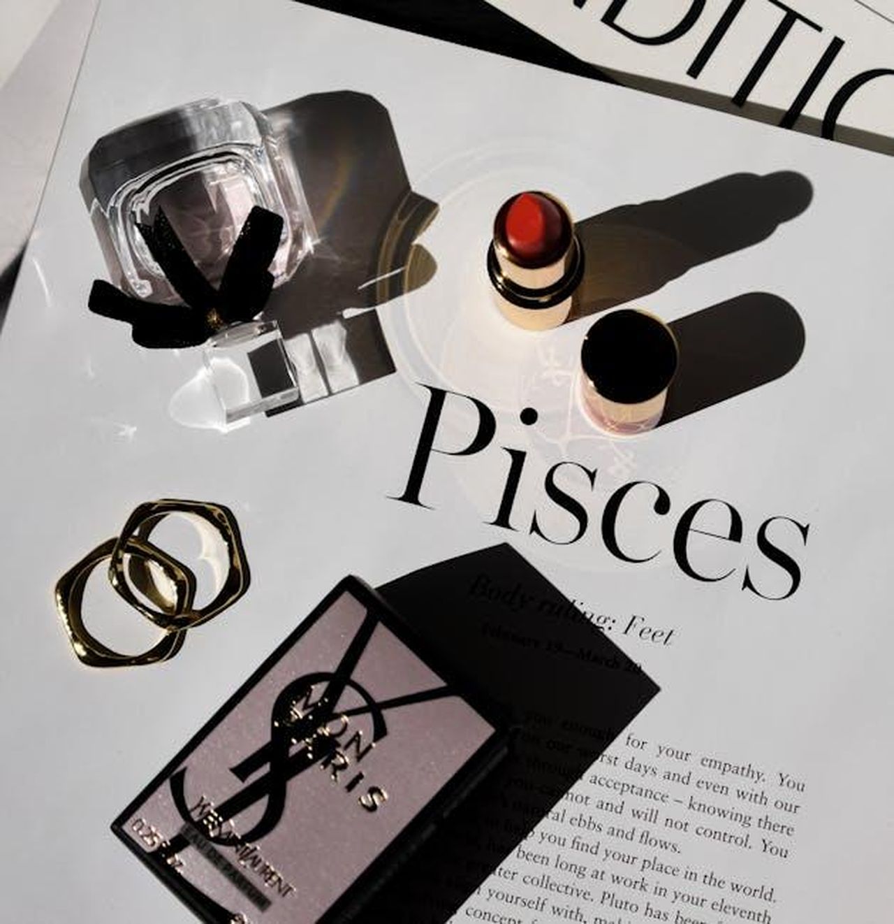 Pesci_19_febbraio__20_marzo_j1UCgNM6wJ - Confidenze24 Source: Harper Sunday - pexels - Chic still life showcasing perfume and lipstick on a magazine with Pisces theme, creating a modern aesthetic.