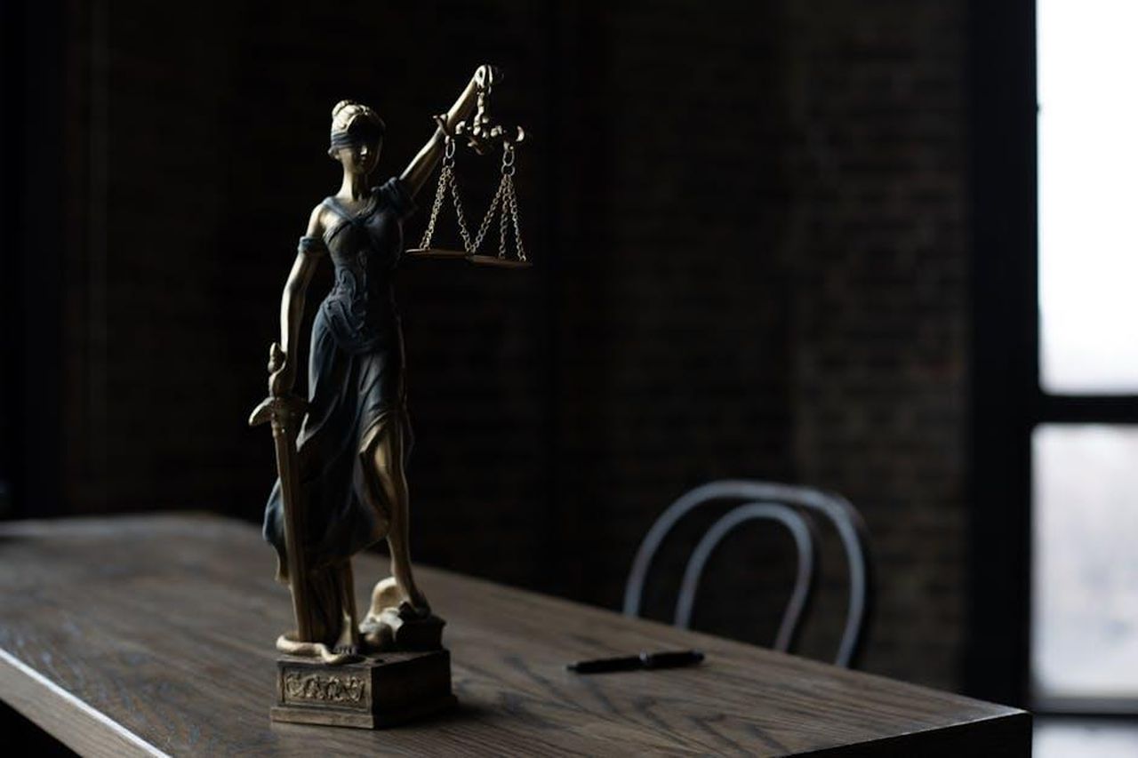 Porsha_Dice_Che_la_Verit_Sar_Rivelata_Abv7vRtLB9 - Confidenze24 Source: KATRIN BOLOVTSOVA - pexels - Lady Justice figurine on wooden table in dimly lit room symbolizes law and fairness.
