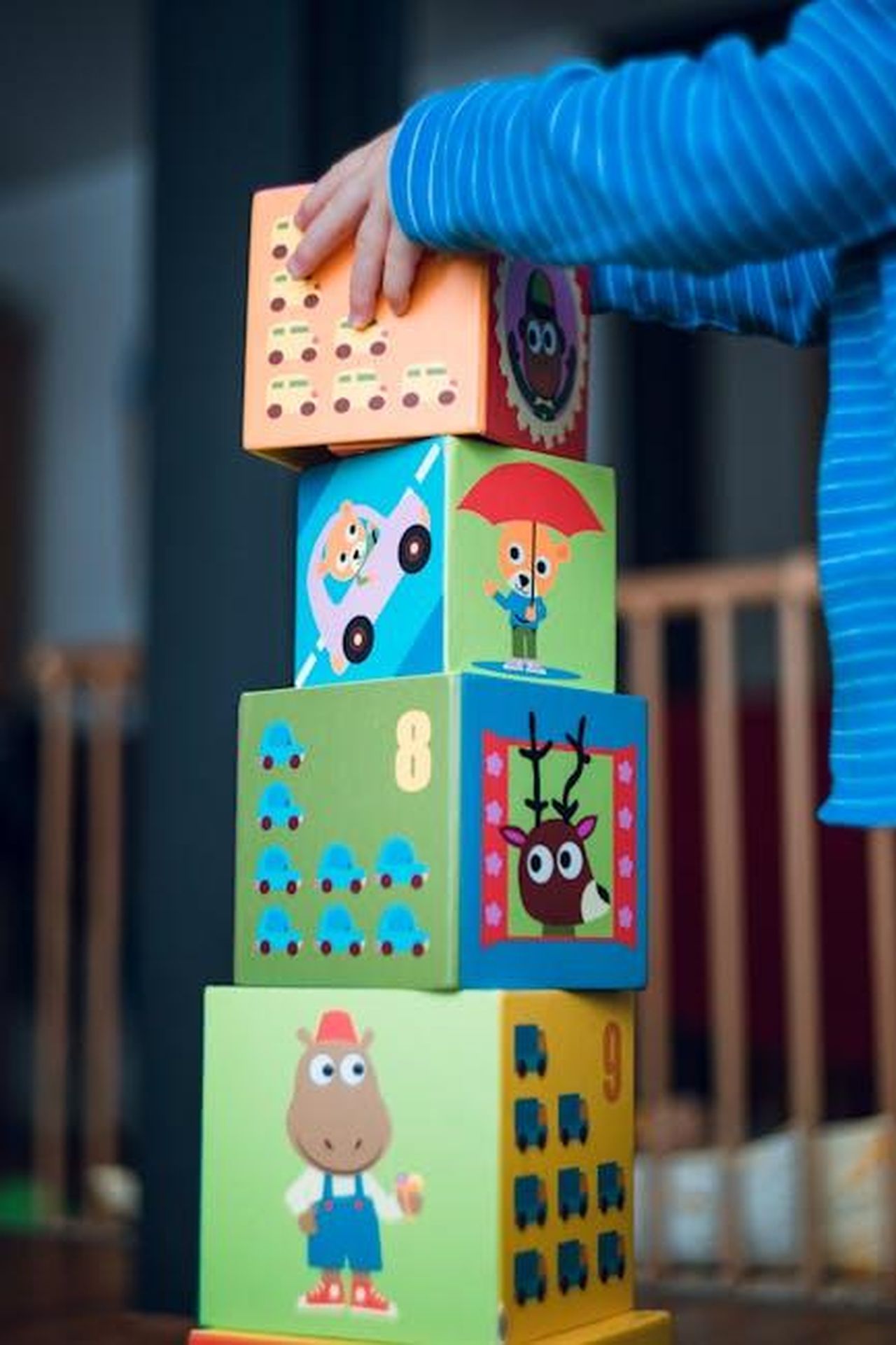 Possibili_Ritorni_di_Personaggi_Famosi_t5ZikYI9lW - Confidenze24 Source: Markus Spiske - pexels - A child playing indoors, stacking colorful wooden toy blocks with joyful illustrations.