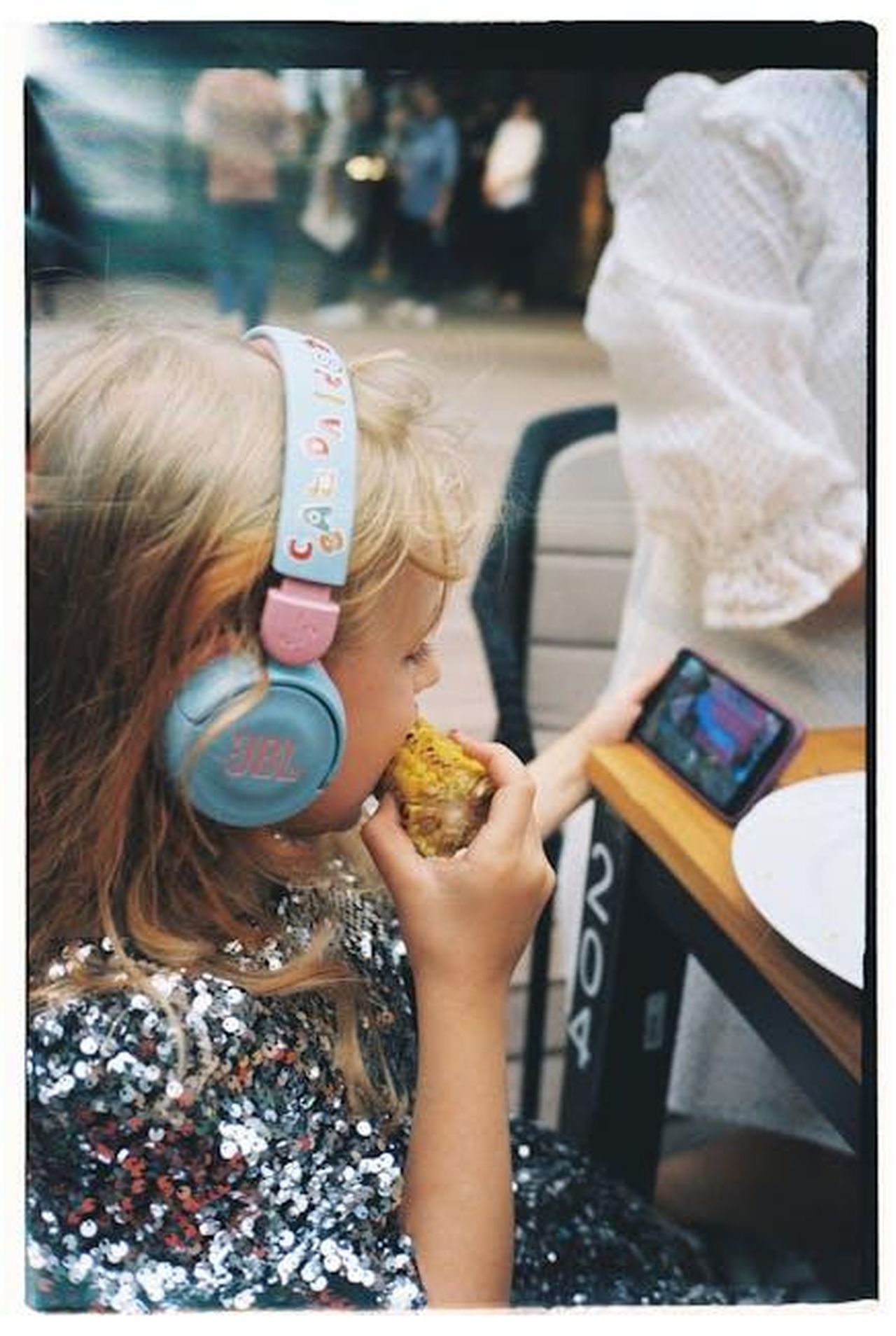 Preoccupazioni_dei_genitori_riguardo_ai_media_digitali_wtig9gS6CY - Confidenze24 Source: Polina Chistyakova - pexels - Young girl wearing headphones eating corn and watching a video on a smartphone.