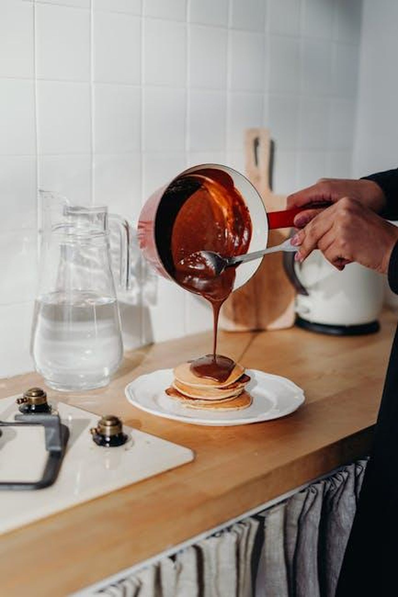 Preparare_la_colazione_per_la_famiglia_uT2c1CMtrR - Confidenze24 Source: cottonbro studio - pexels - Homemade pancakes with chocolate syrup being poured in cozy kitchen setting.