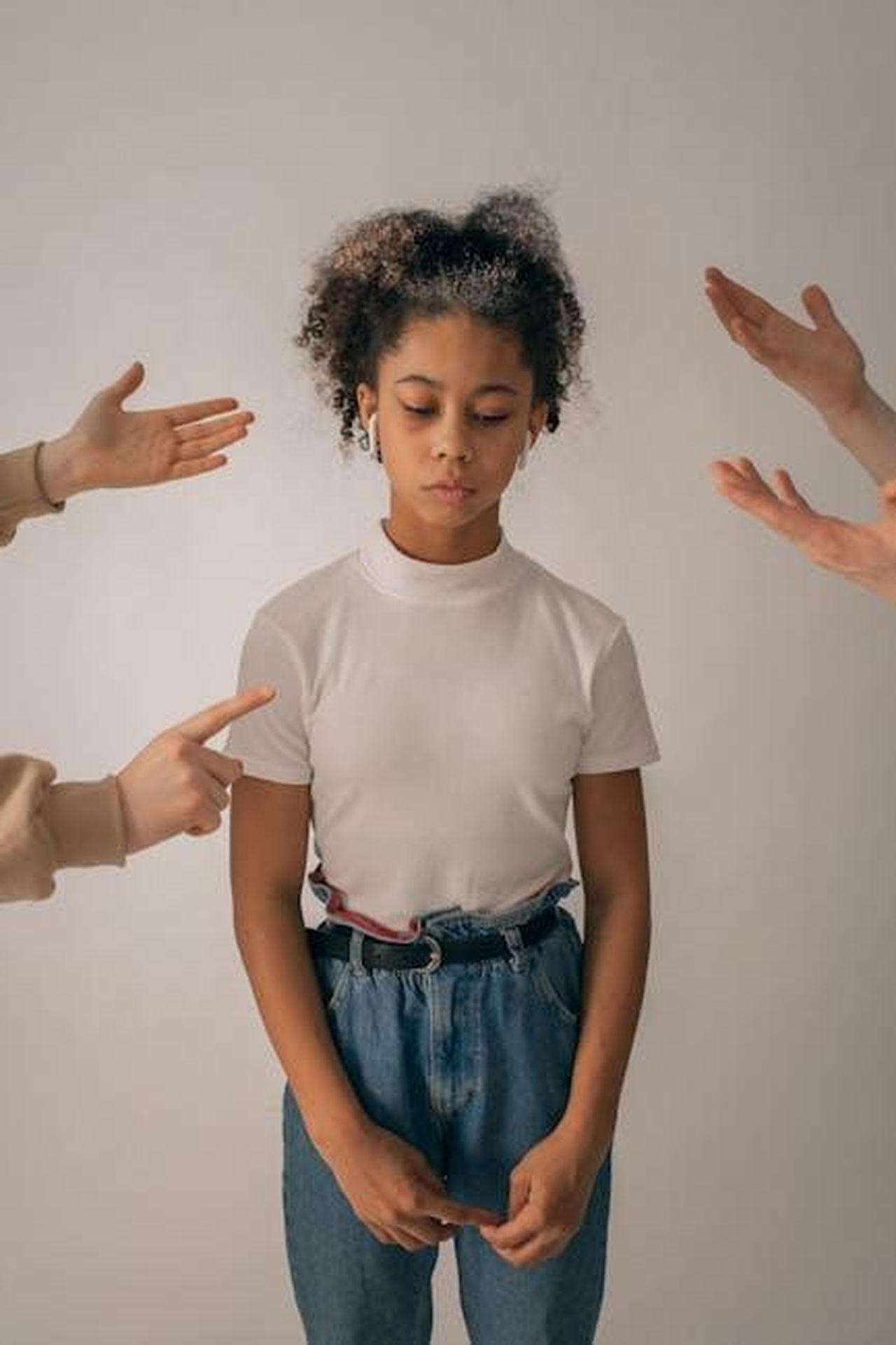 Pressione_sociale_e_aspettative_sessuali_66j8NNxeUw - Confidenze24 Source: Monstera Production - pexels - Crop people scolding disappointed African American teenage girl in casual wear standing on white background with sad face in studio