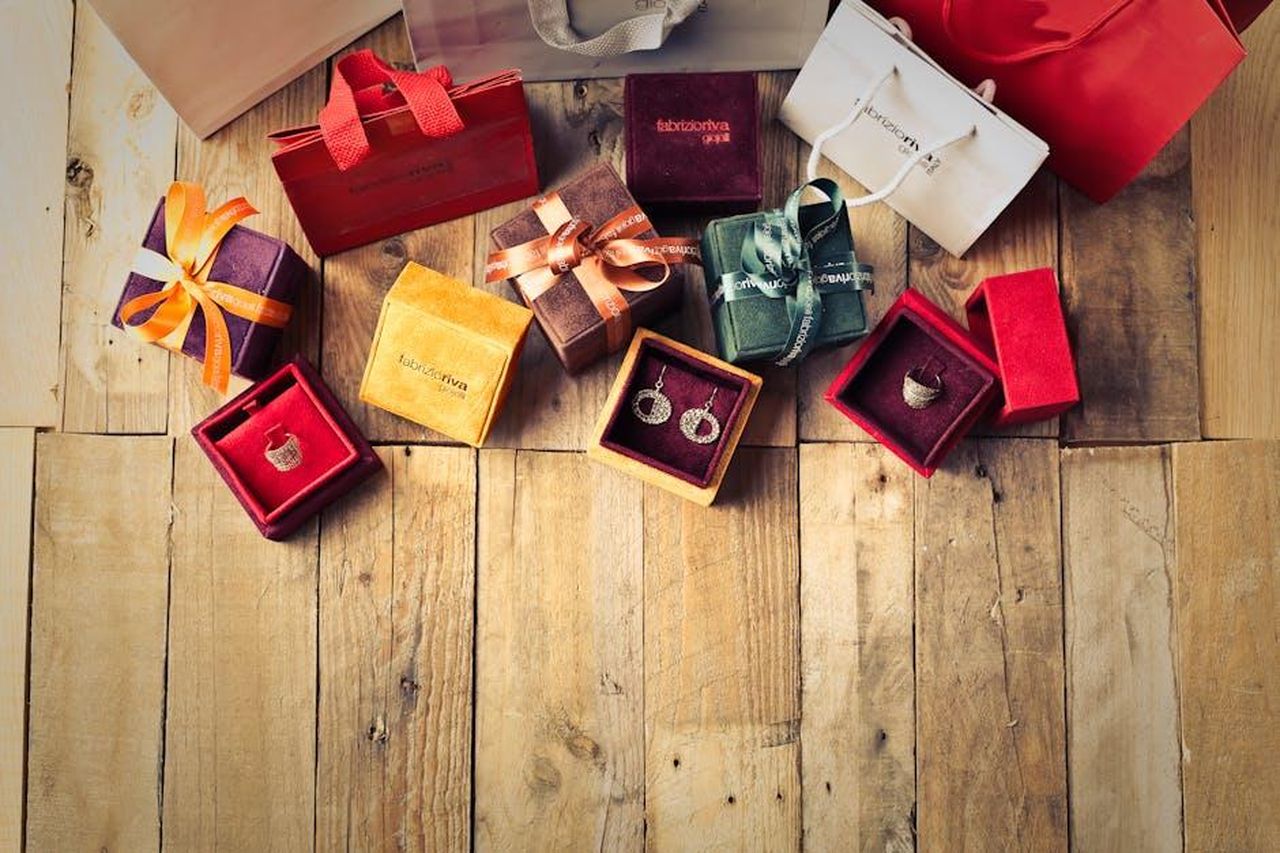 Prezzi_e_disponibilit_affrettati_a_fare_acquisti_pihnWPgXgB - Confidenze24 Source: Andrea Piacquadio - pexels - Elegant jewelry gifts with shopping bags on wooden floor, perfect for holiday celebrations.