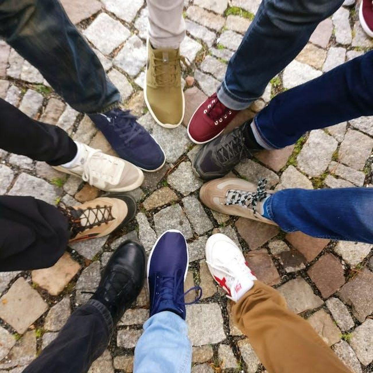 Prezzo_e_comfort_delle_nuove_sneakers_Fj1HDTeGBv - Confidenze24 Source: Ingo Joseph - pexels - Circle of sneakers on cobblestone pavement representing diversity and urban fashion.