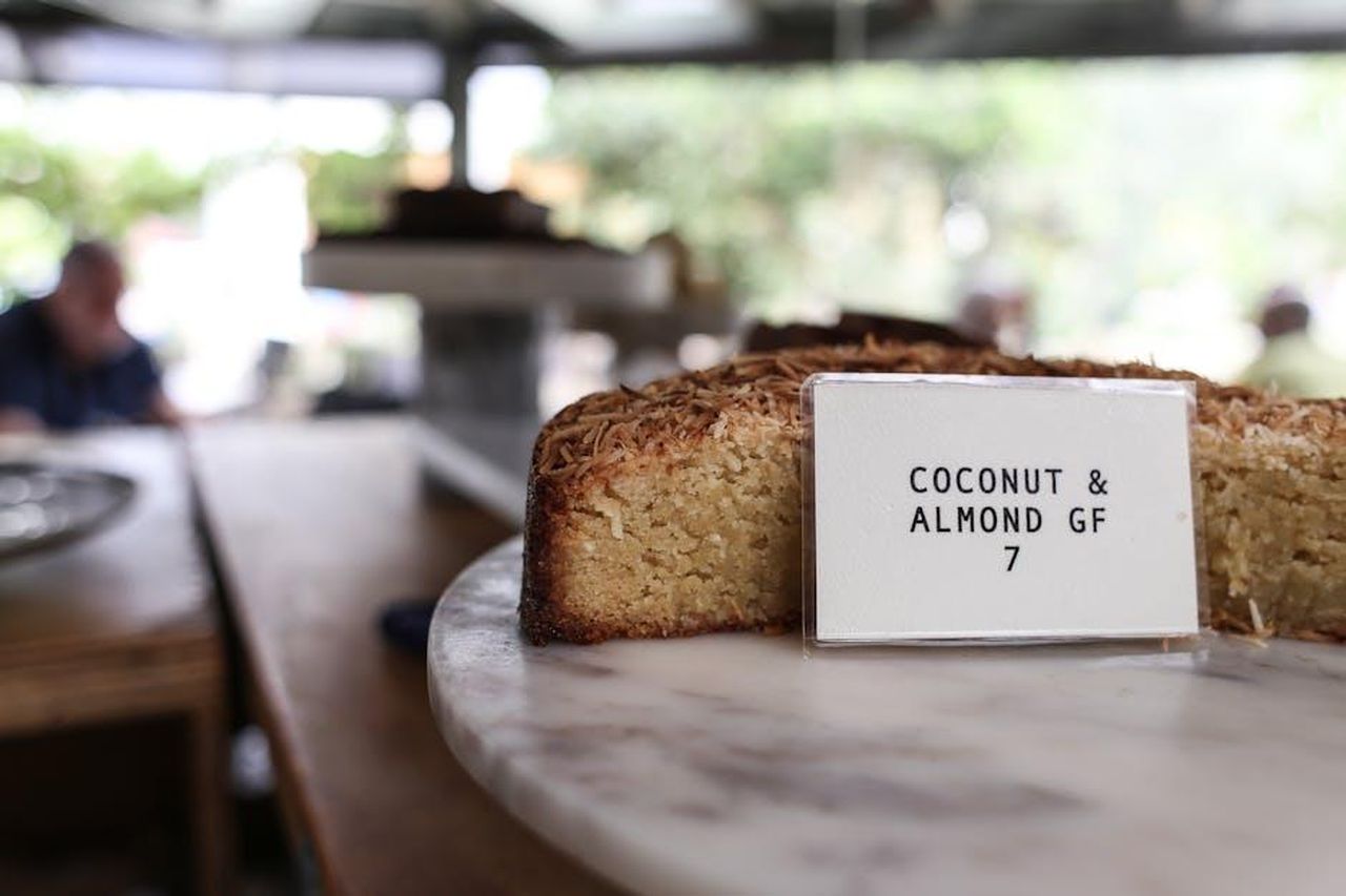 Prezzo_e_disponibilit_della_Torta_di_Carote_s2KyNvZWol - Confidenze24 Source: Rachel Claire - pexels - Close-up of a gluten-free coconut almond cake slice on display with a price tag.