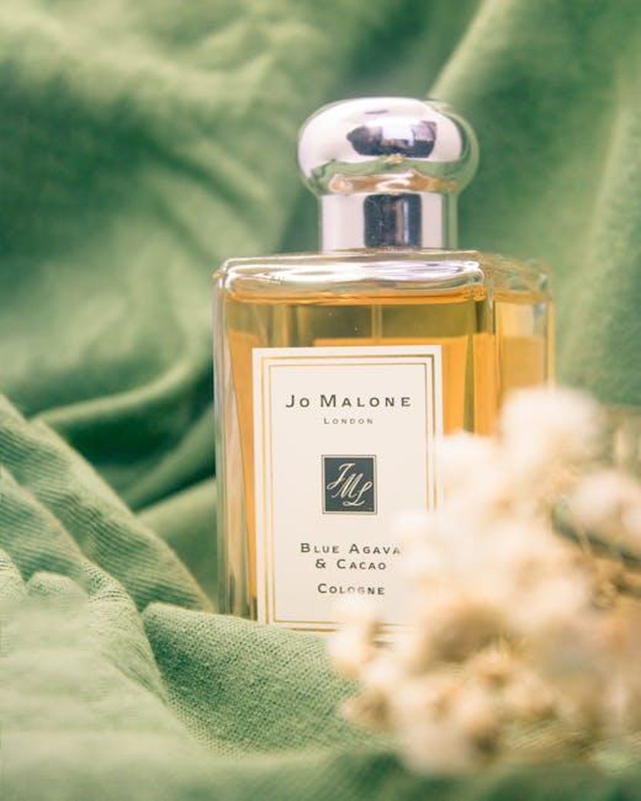 Profumi_Jo_Malone_in_offerta_scopri_le_occasioni_RrYcOX1C1U - Confidenze24 Source: Bảo Phúc - pexels - A luxurious Jo Malone perfume bottle styled on soft green fabric for an elegant still life shot.