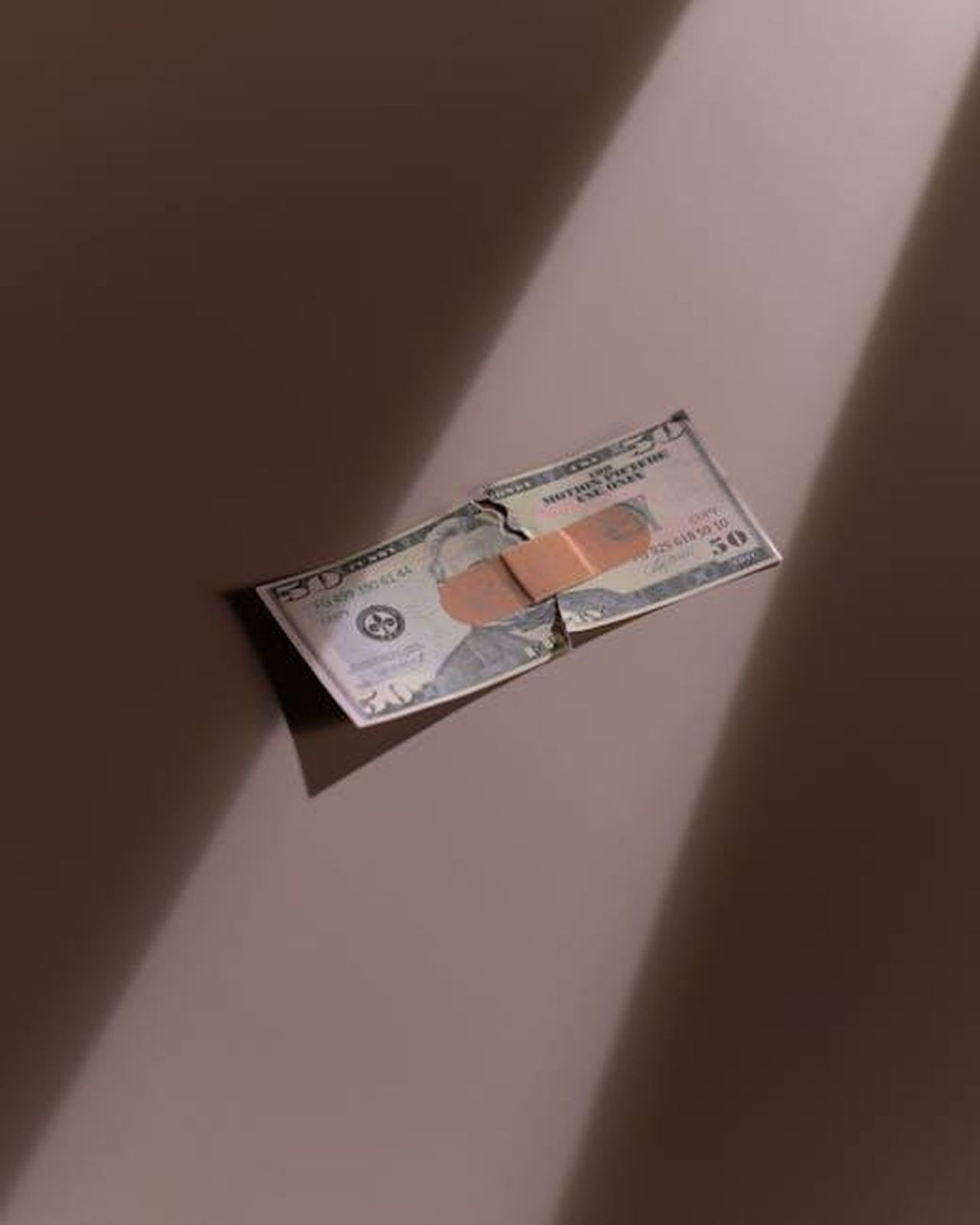 Qual__il_patrimonio_netto_di_Iwan_Carrington_UWtRRakRoo - Confidenze24 Source: cottonbro studio - pexels - A torn dollar bill patched with a bandage, symbolizing financial recovery.