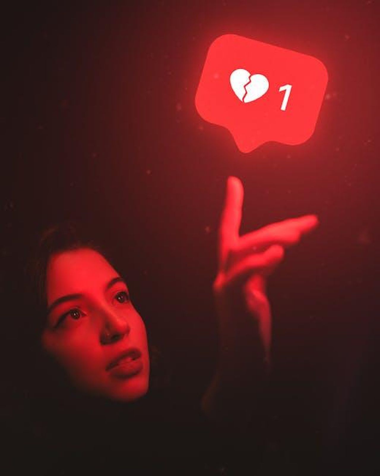 Qualcosa_non_va_c29Vkgon4G - Confidenze24 Source: Matheus Bertelli - pexels - Red-hued image of a woman reaching towards a broken heart icon symbolizing digital detachment.