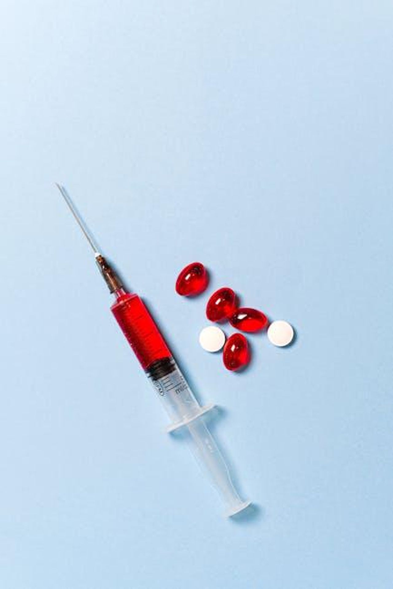 Quali_sono_i_sintomi_della_tubercolosi_PNzzUNk2cf - Confidenze24 Source: Anna Shvets - pexels - Syringe with red liquid and pills on a blue backdrop symbolizing medical treatment.