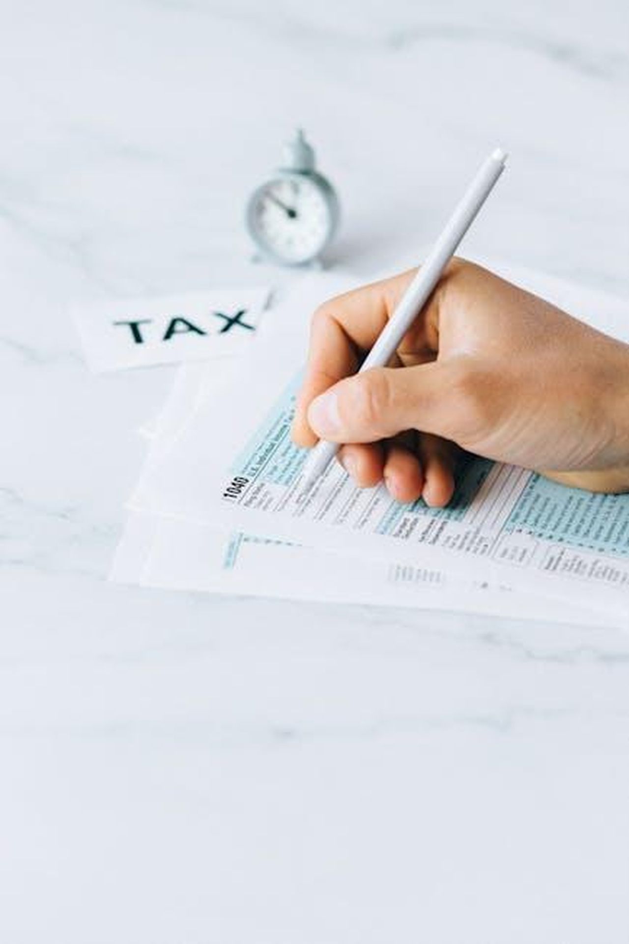 Quando_Torner_Matlock_xXj82xf4pw - Confidenze24 Source: Nataliya Vaitkevich - pexels - Hand completing tax forms with a pen, symbolizing financial deadline and time urgency.