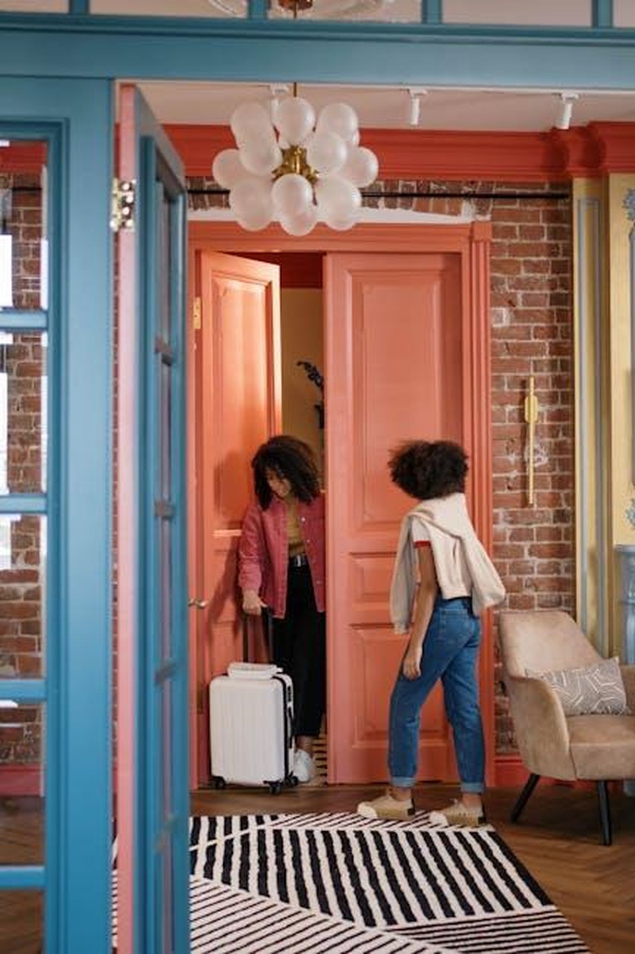 Quando_torner_Bex_in_EastEnders_7zpmCRpbip - Confidenze24 Source: cottonbro studio - pexels - Two women arriving home with a suitcase, greeted by stylish interior design.