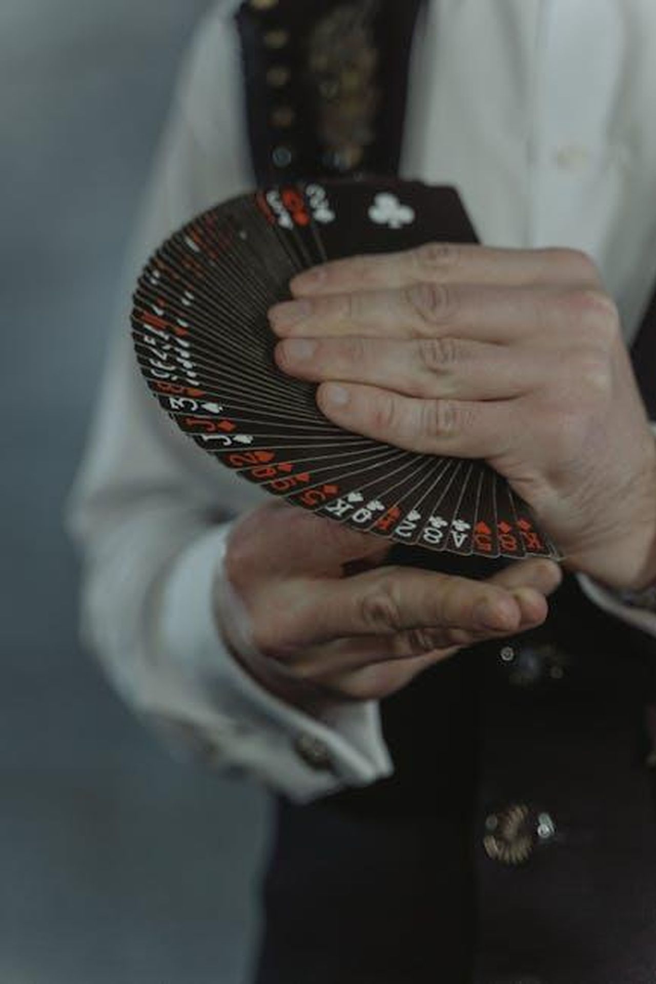 Reazione_mista_al_nuovo_game_show_w7kqMBB0L2 - Confidenze24 Source: Tima Miroshnichenko - pexels - An illusionist elegantly displaying a fan of black playing cards during a magic performance.