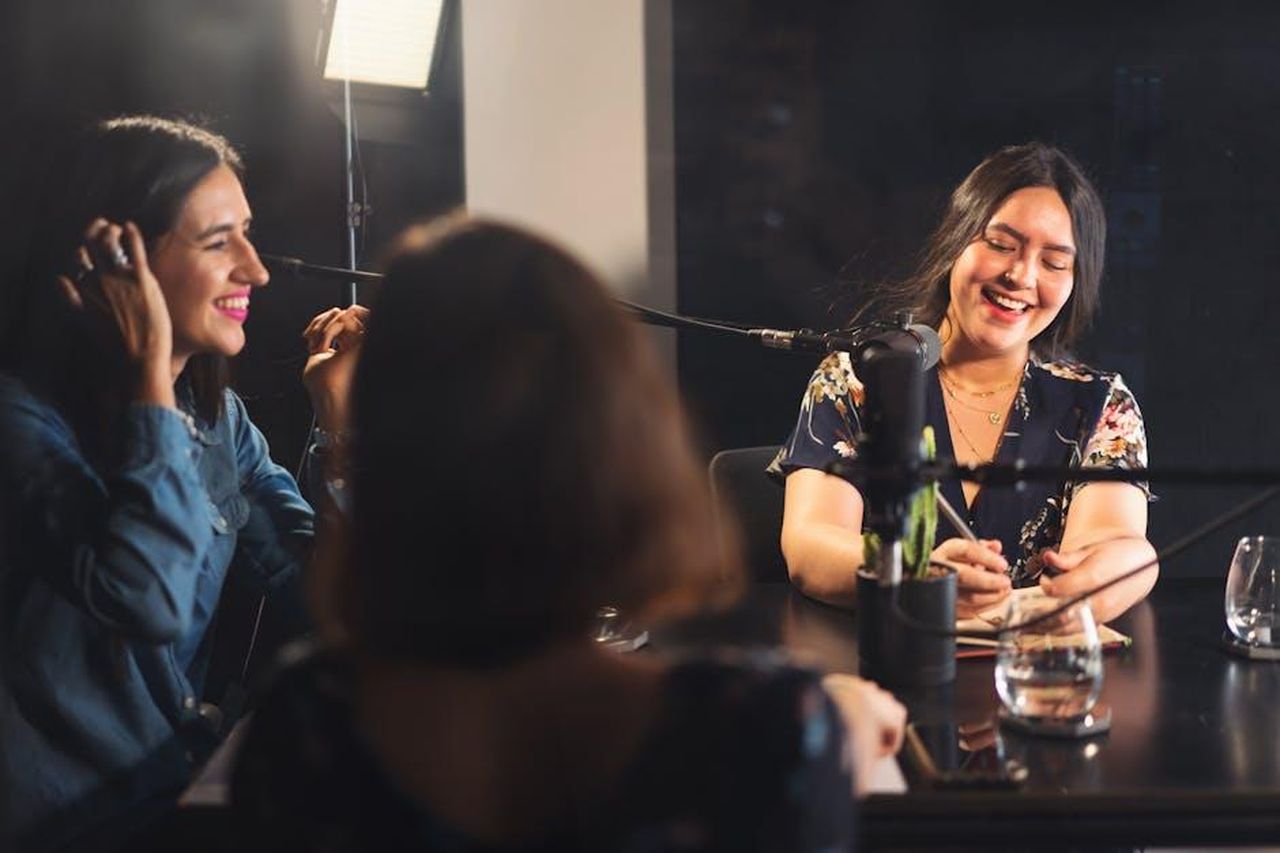 Reazioni_Dalla_Rete_Sulla_Decisione_Di_Dr_G_I1OWx3CpvH - Confidenze24 Source: Los Muertos Crew - pexels - Three women recording a podcast together, sharing smiles and enjoying the moment in a cozy studio setting.