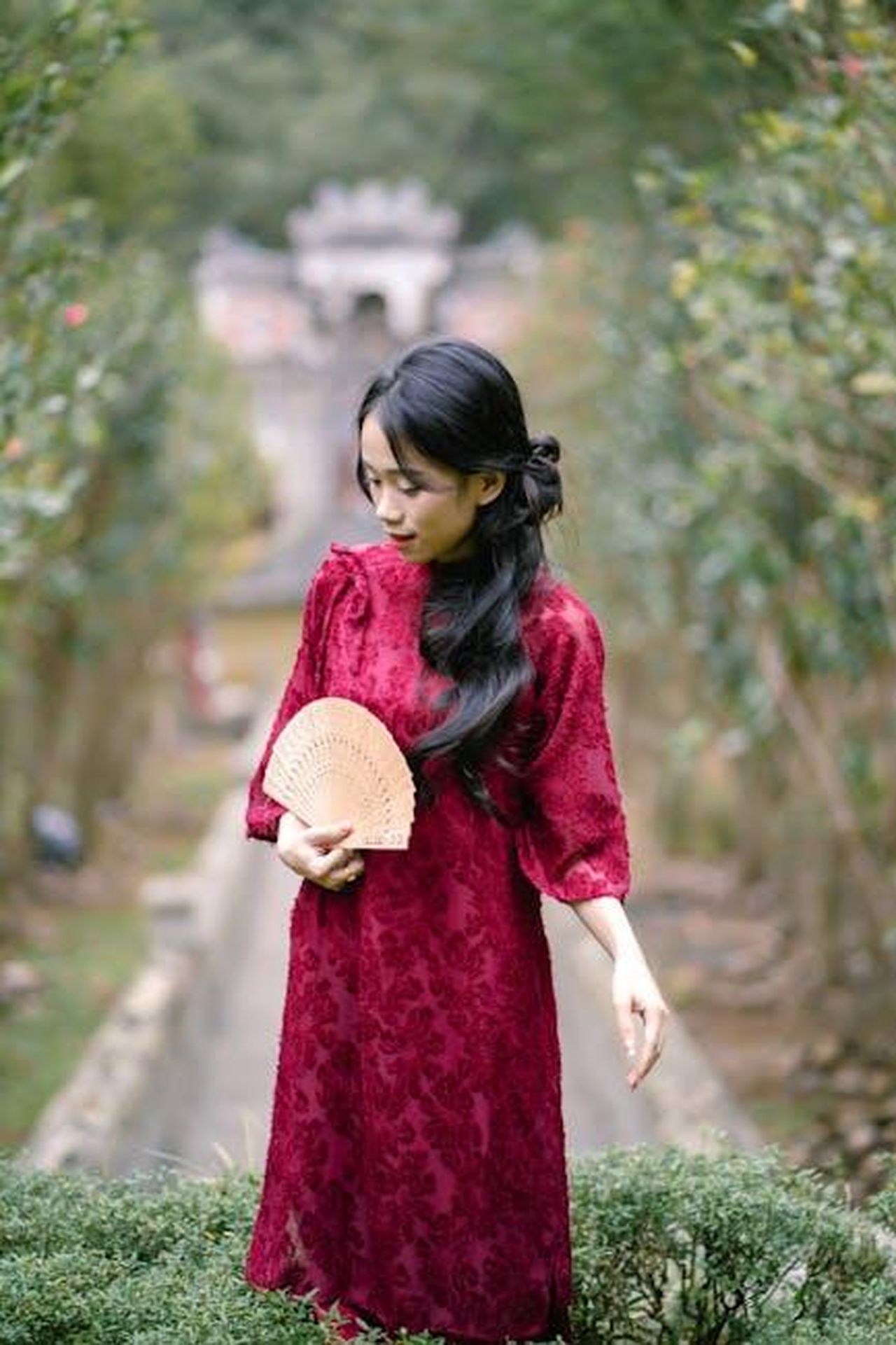 Reazioni_dei_Fan_al_Nuovo_Trailer_RBxFKaaq8E - Confidenze24 Source: Anh Quốc - pexels - Elegant woman in a red dress holding a fan, standing in a lush garden setting.