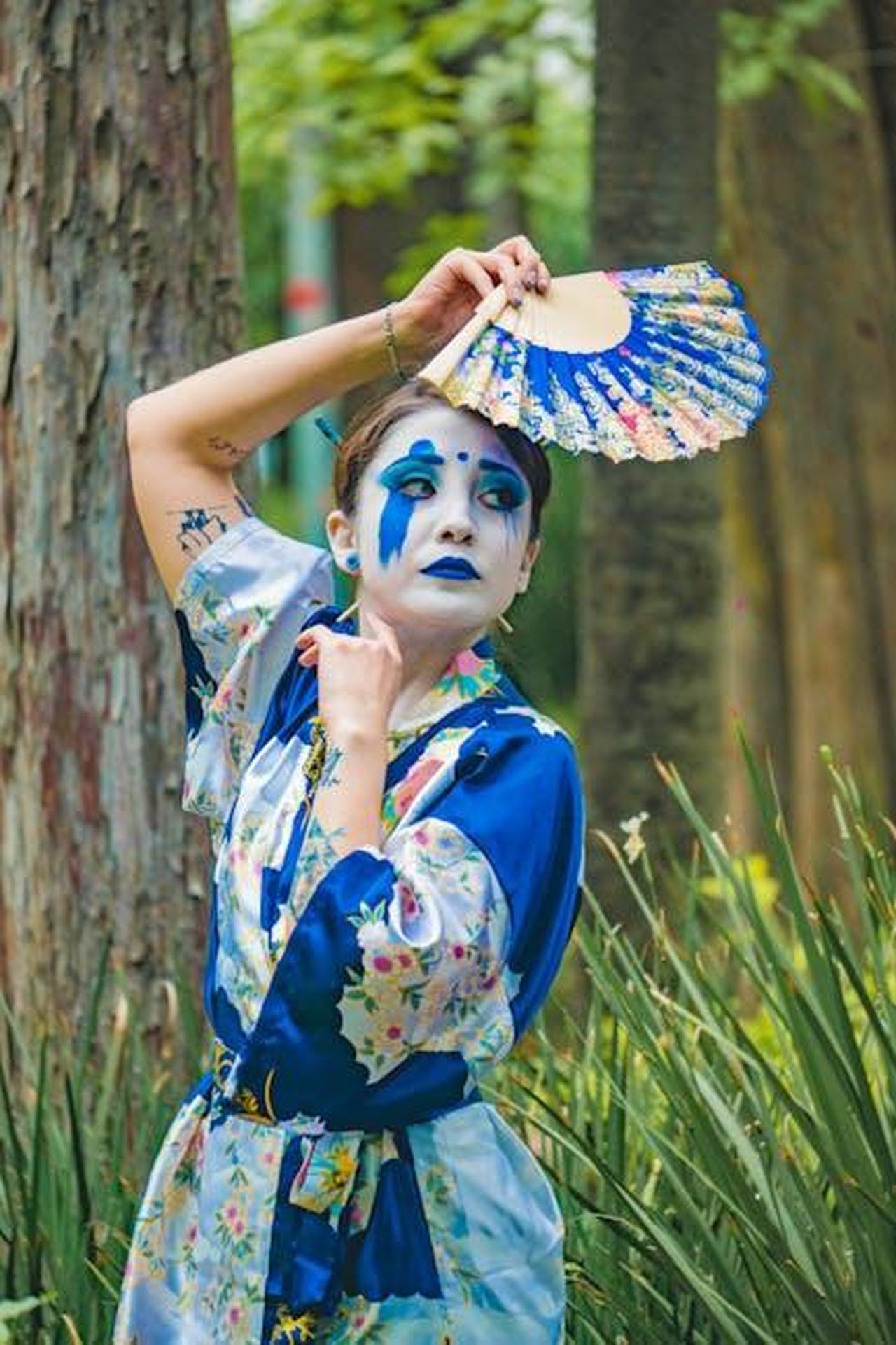 Reazioni_dei_fan_alla_rivelazione_di_Jack_P_Shepherd_vPZuHJKRZh - Confidenze24 Source: Yuriko Salazar Luna - pexels - Vibrant portrait of a person in blue floral attire with dramatic makeup and handheld fan, outdoors.