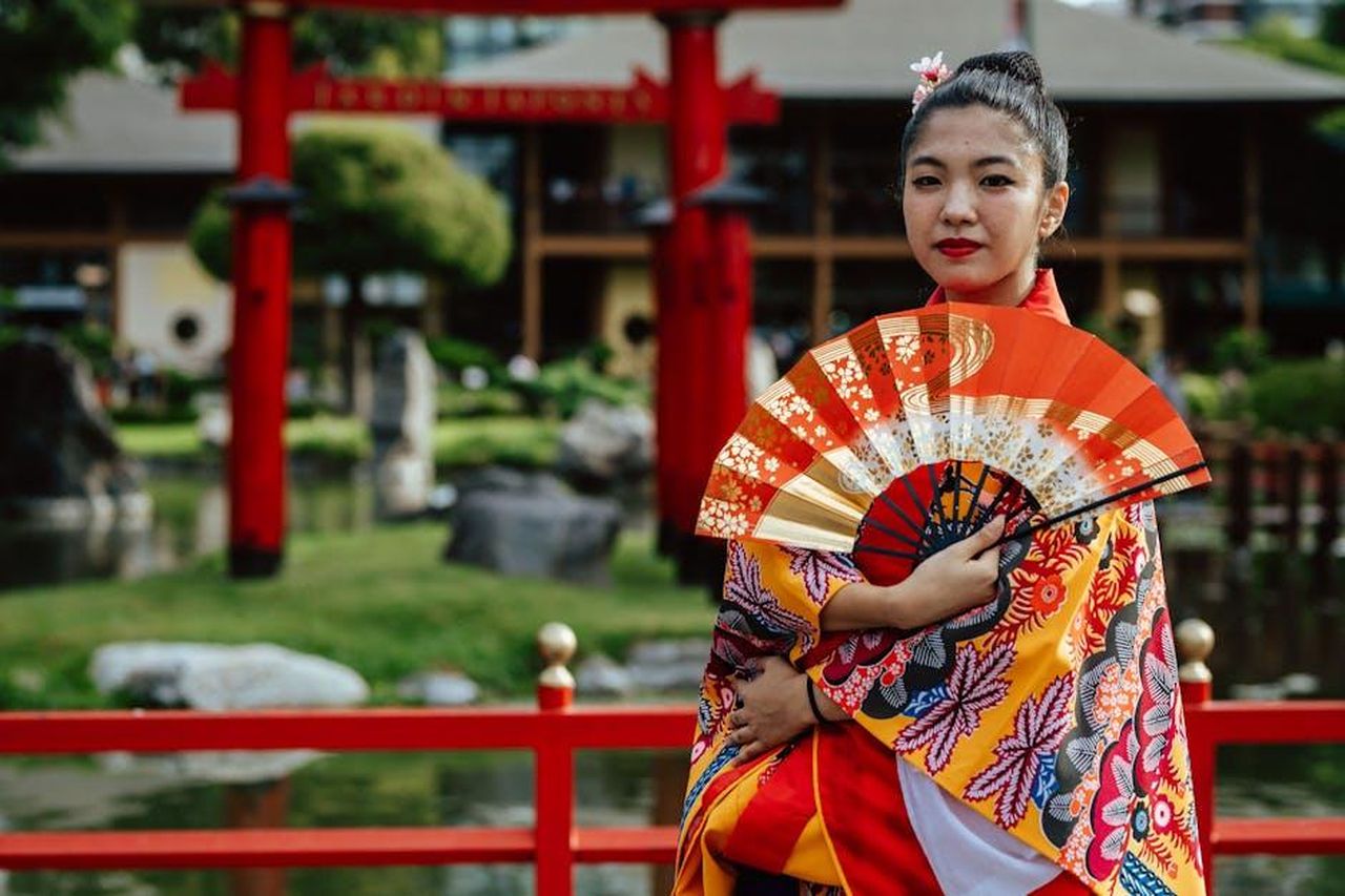 Reazioni_dei_fan_e_richieste_speciali_zU1bnW793H - Confidenze24 Source: Gera Cejas - pexels - Woman in traditional attire with a fan in Buenos Aires Japanese Garden.