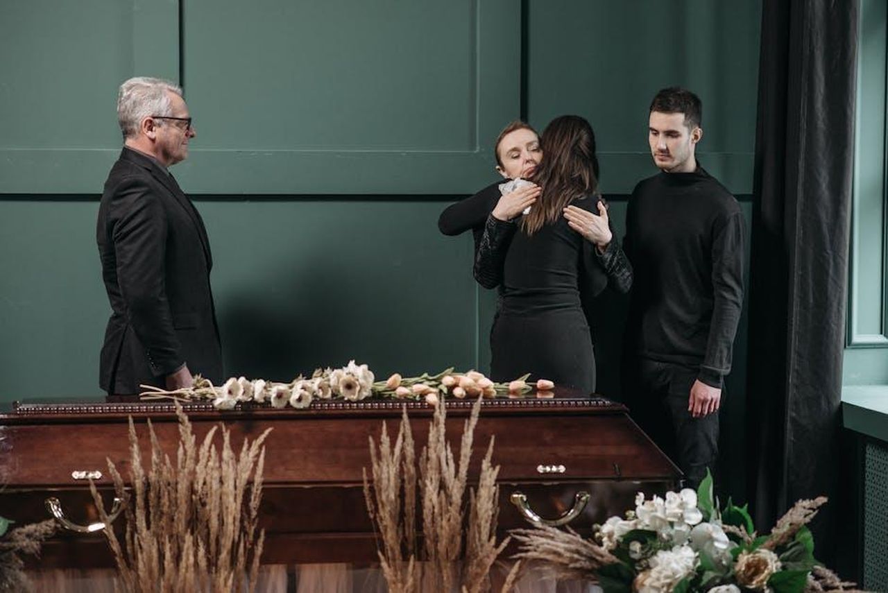 Reazioni_e_condoglianze_per_Sayso_P_e_Sauce_Walka_NdV9GMqxUK - Confidenze24 Source: Pavel Danilyuk - pexels - A heartfelt moment of comfort and empathy during a funeral service indoors.