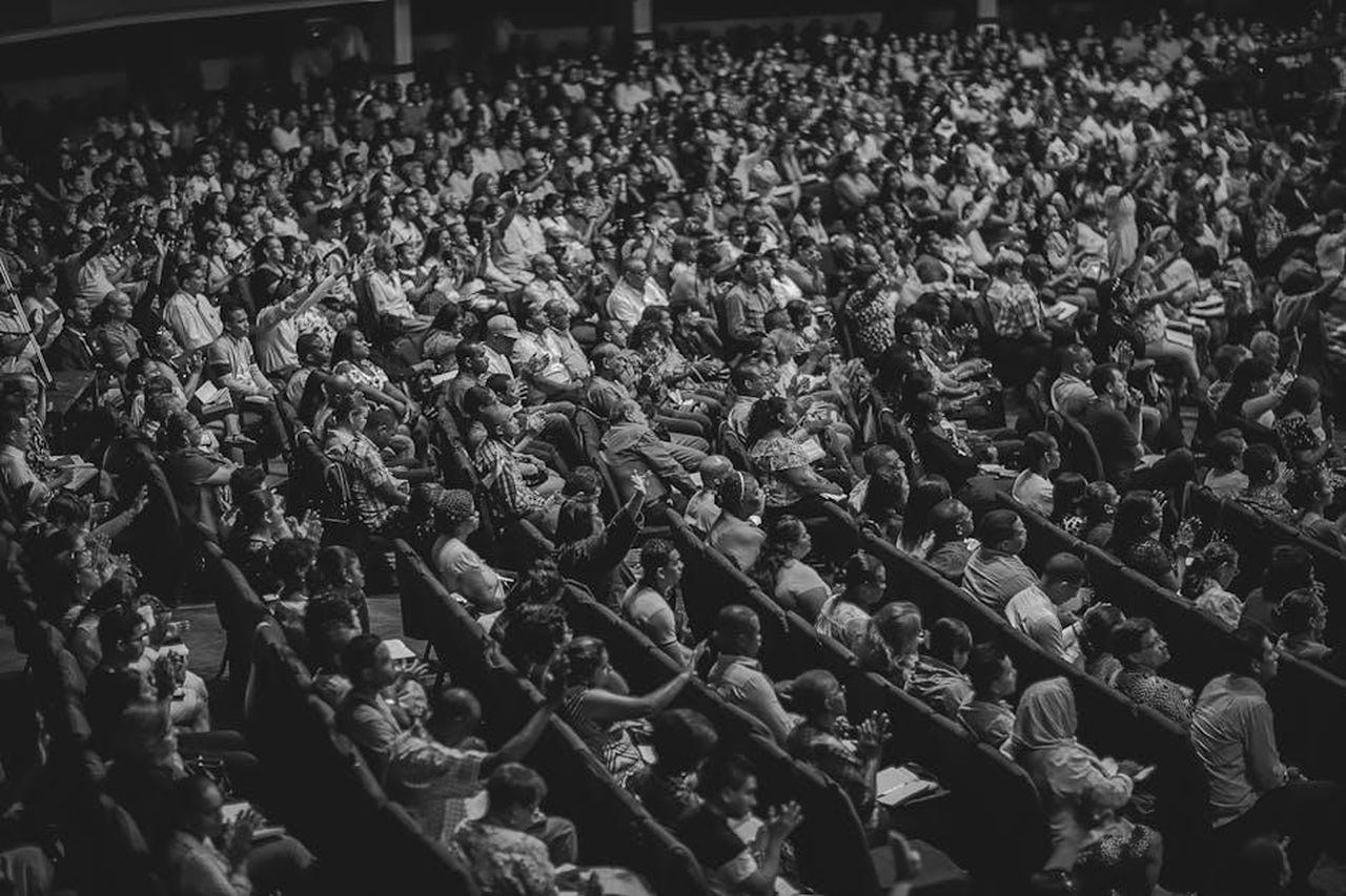 Reazioni_entusiastiche_dei_fan_di_Mickey_Callisto_FulCZnBF8X - Confidenze24 Source: Luis Quintero - pexels - High angle view of a diverse audience in a theater setting, captured in monochrome.