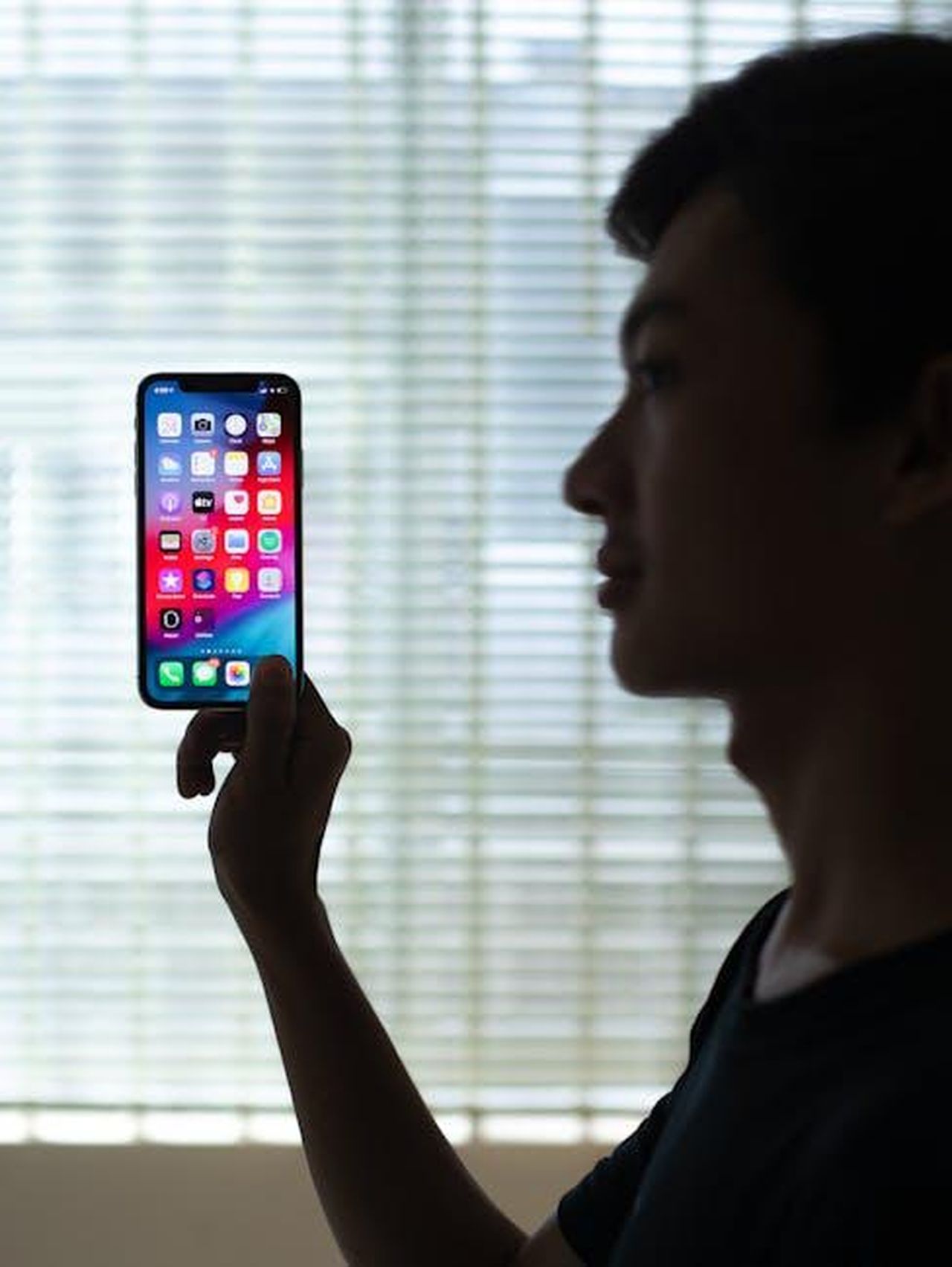Reazioni_sui_social_media_95Bx2Avmtf - Confidenze24 Source: I'm Zion - pexels - Profile of a man holding a smartphone with colorful apps, backlit indoors.