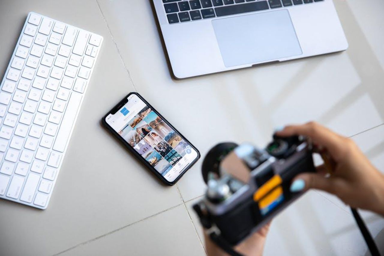 Reazioni_sui_social_media_al_video_di_Marvin_Sapp_NfSzChQsGJ - Confidenze24 Source: Plann - pexels - Person using vintage camera with smartphone and laptop in creative setup.