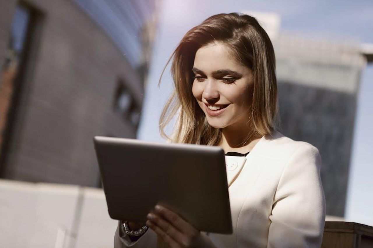 Reazioni_sui_social_media_umi6rQAkBb - Confidenze24 Source: Andrea Piacquadio - pexels - A woman joyfully using a digital tablet outdoors in the city during the day.