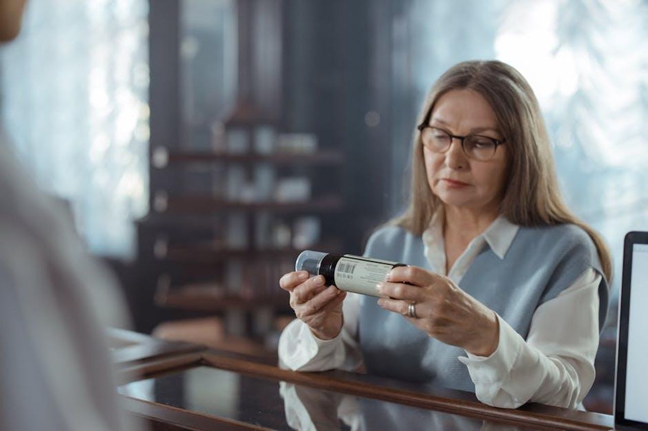 Recensioni_dei_clienti_R9z3ygkTjj - Confidenze24 Source: cottonbro studio - pexels - A senior woman with eyeglasses reviews a medicine bottle at a pharmacy counter indoors.