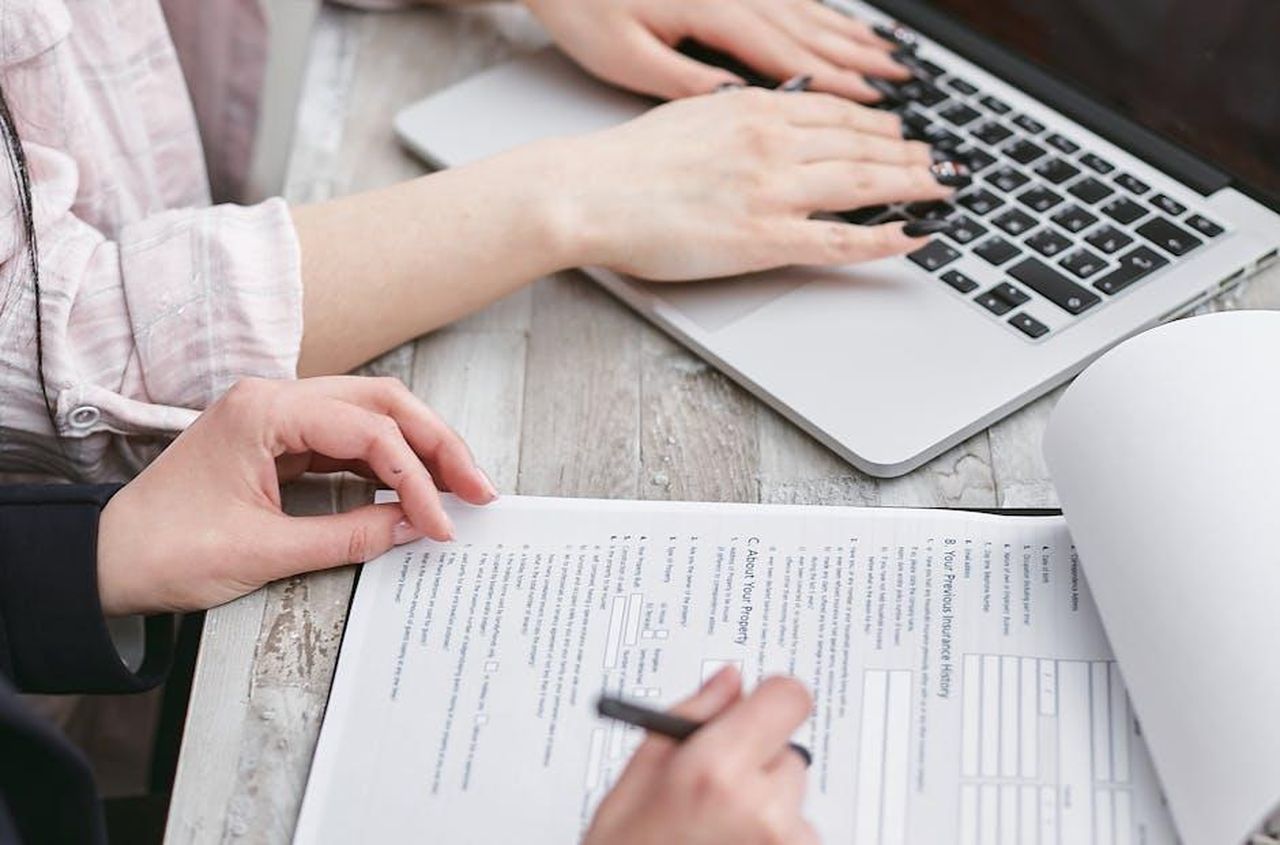 Recensioni_dei_clienti_sul_balsamo_labbra_elf_V8tDBzr1nj - Confidenze24 Source: Mikhail Nilov - pexels - Close-up of hands typing on a laptop and reviewing business documents, focused on finance and legal tasks.