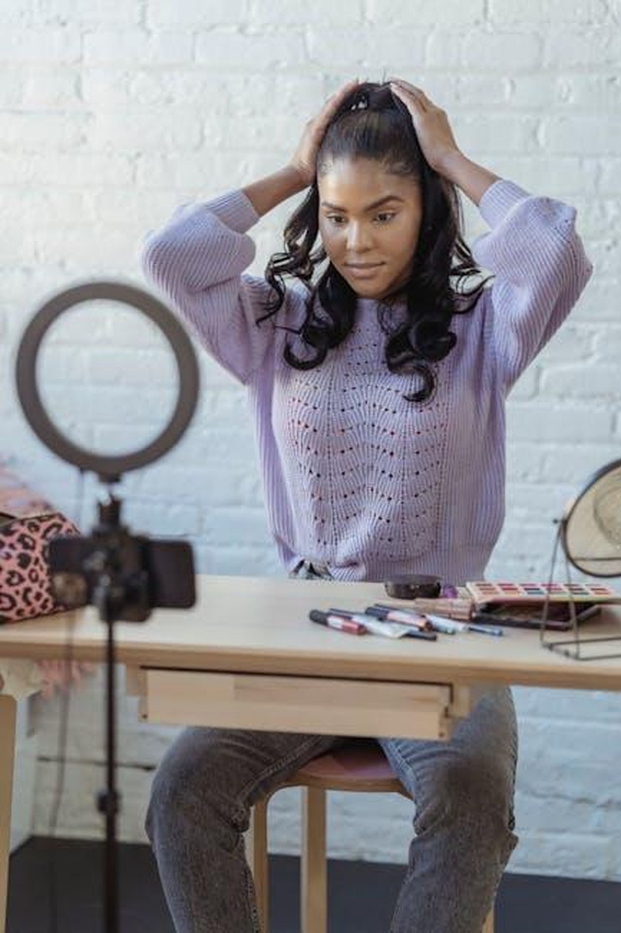 Recensioni_e_opinioni_degli_utenti_woyHyrC2v2 - Confidenze24 Source: George Milton - pexels - Stylish young African American female influencer in sweater adjusting long dark hair while sitting at wooden table before recording makeup tutorial video on smartphone