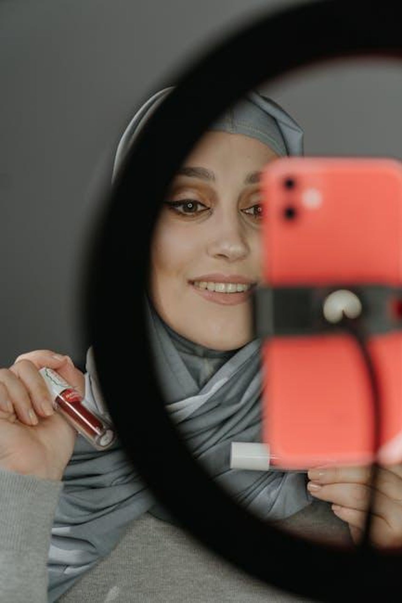 Recensioni_entusiaste_degli_acquirenti_Tsuj47yOpr - Confidenze24 Source: cottonbro studio - pexels - A Muslim woman in traditional clothing taking a selfie while showcasing lip gloss in front of a ring light.