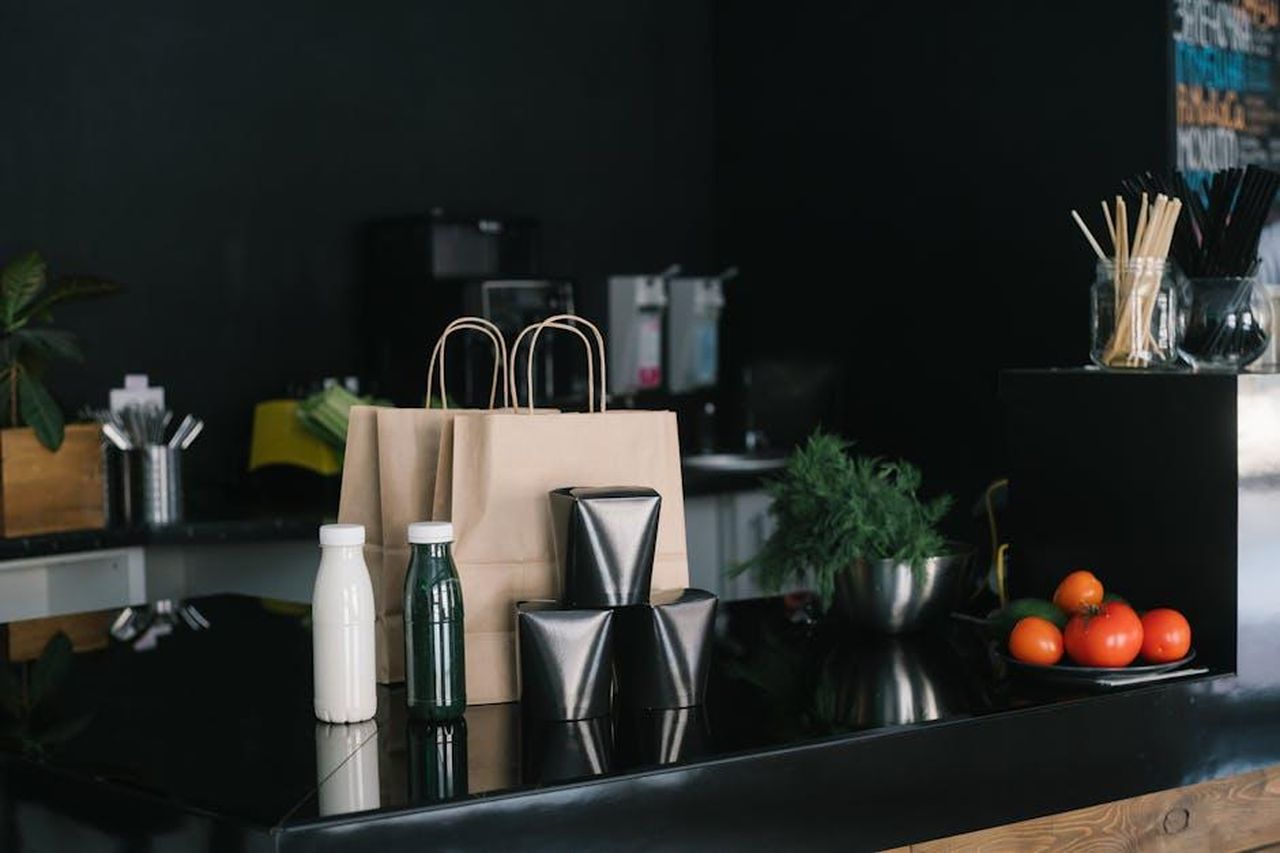 Recensioni_entusiaste_per_il_Dutch_Oven_AVVyg3uAyF - Confidenze24 Source: Mikhail Nilov - pexels - Eco-friendly takeaway packaging in a modern kitchen setting with fresh ingredients and cutlery.