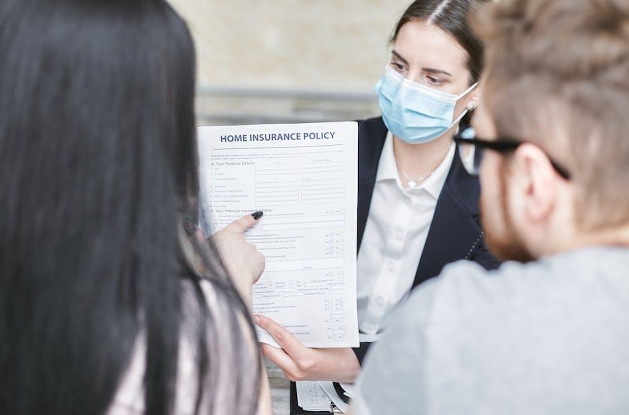 Recensioni_entusiastiche_degli_utenti_1zRr04CuOW - Confidenze24 Source: Mikhail Nilov - pexels - A professional woman explains a home insurance policy to clients during a meeting. Indoors setting.