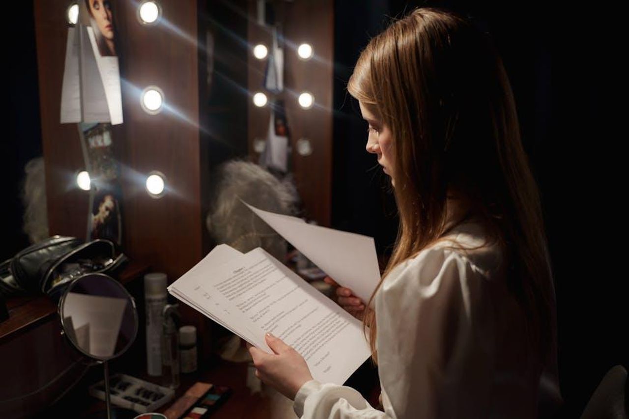 Recensioni_entusiastiche_degli_utenti_GY7uEErEaE - Confidenze24 Source: cottonbro studio - pexels - Actress reading script in a dressing room, surrounded by makeup and lights.