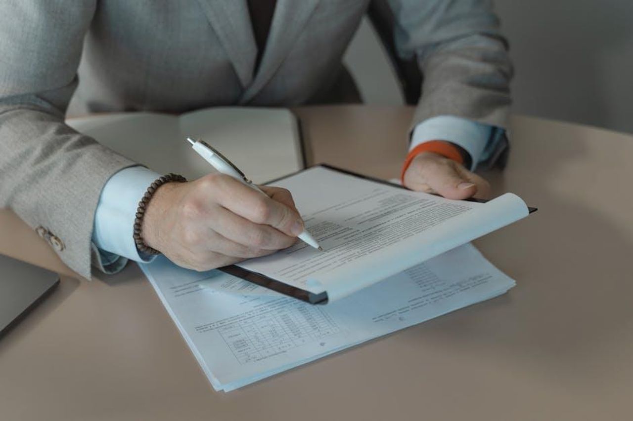 Recensioni_entusiastiche_dei_clienti_m2MA0qOupc - Confidenze24 Source: Tima Miroshnichenko - pexels - Close-up of business person signing documents at a desk with a pen.