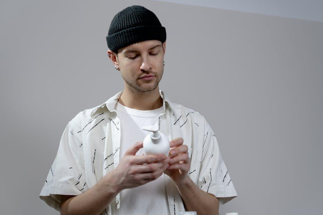 Recensioni_entusiastiche_per_il_Medicube_Collagen_Jelly_Cream_OuECAkl9M1 - Confidenze24 Source: cottonbro studio - pexels - A young man examines a shampoo bottle in a modern indoor setting, wearing casual attire.
