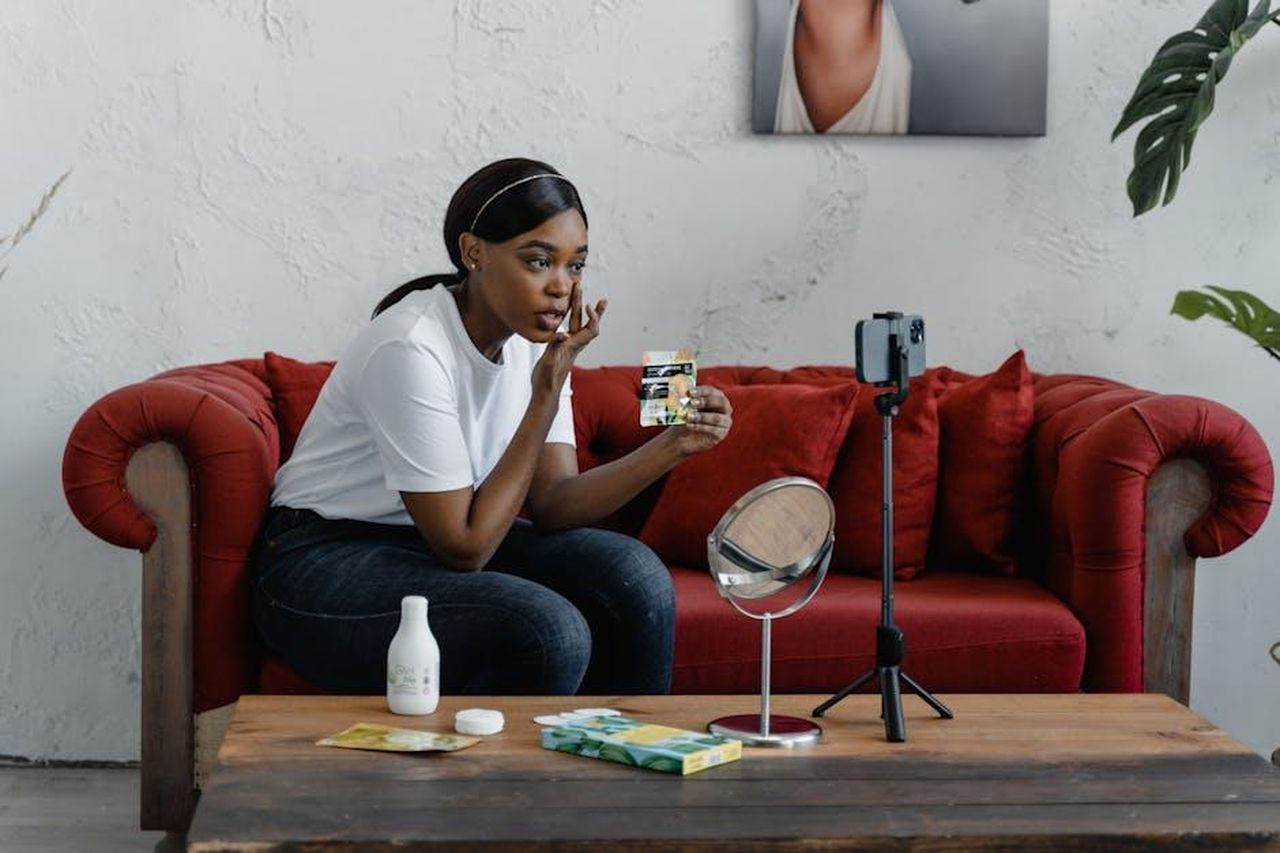 Recensioni_entusiastiche_sul_TruSkin_Retinol_Serum_rHCTmyVcxn - Confidenze24 Source: Tima Miroshnichenko - pexels - A woman records a makeup tutorial in a cozy indoor setting with cosmetics and a smartphone stand.