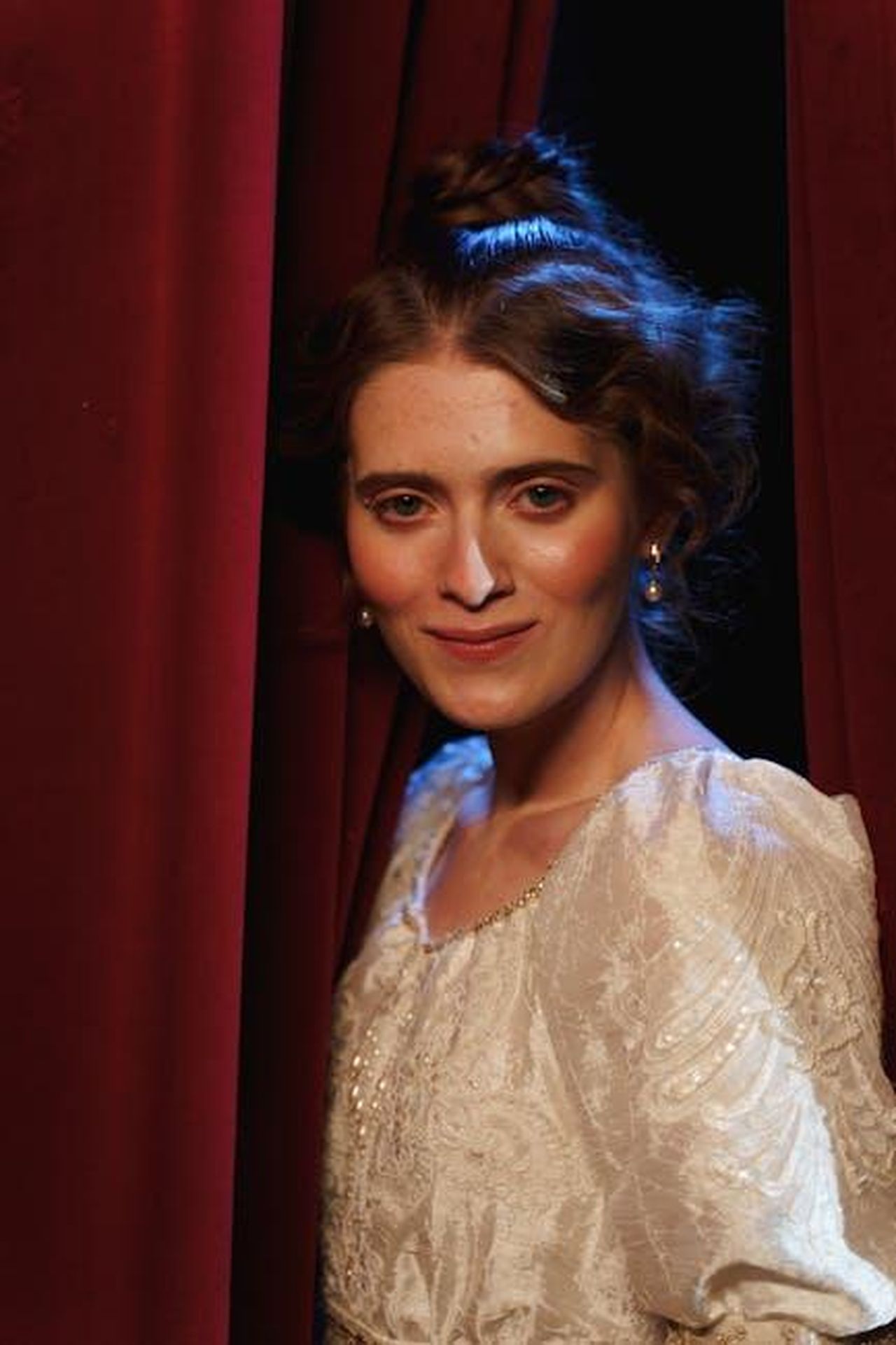 Reginae_parla_del_suo_ruolo_in_Nothing_Even_Matters_Hc8kDOoQPT - Confidenze24 Source: cottonbro studio - pexels - Portrait of a woman in vintage costume amidst theater curtains, exuding classical elegance.