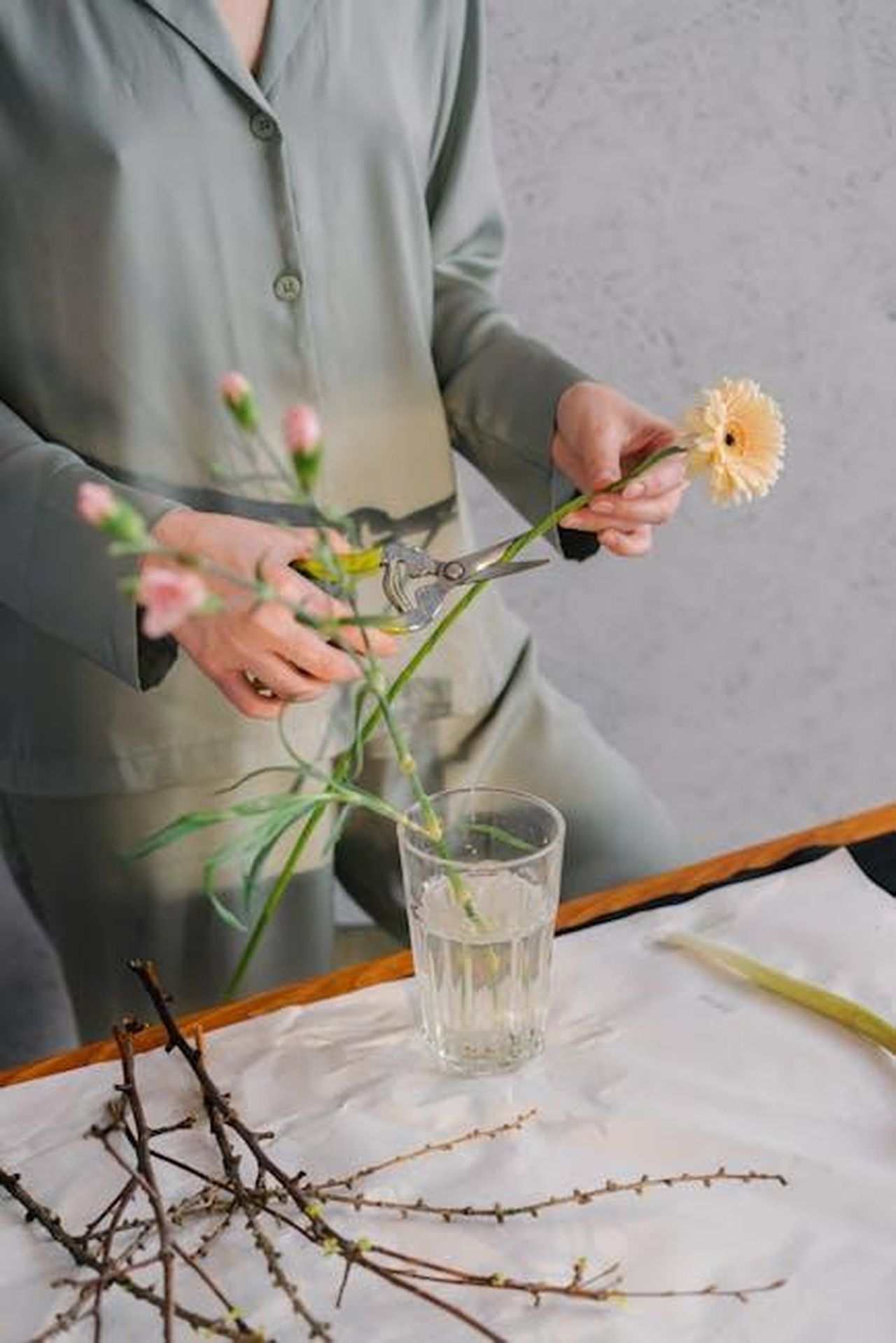 Relaxare_con_larrangiamento_dei_fiori_xnHWx1LjUE - Confidenze24 Source: Mikhail Nilov - pexels - A woman in green outfit trimming flowers for a floral arrangement indoors.