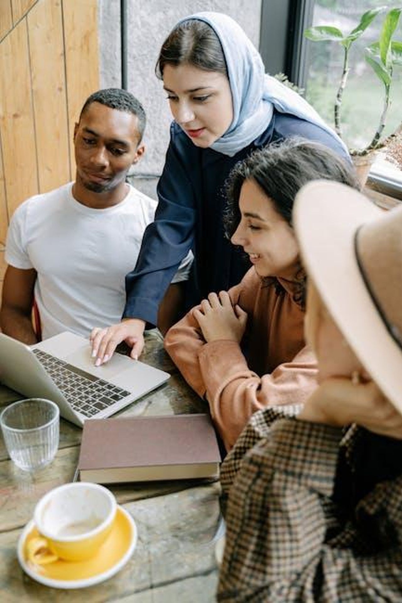 Relazione_tra_Reenie_ed_Elliott_nella_stagione_2_6bAGPDe46O - Confidenze24 Source: Ivan Samkov - pexels - A diverse group of young adults collaborating on a project in a cozy, sunlit cafe environment.