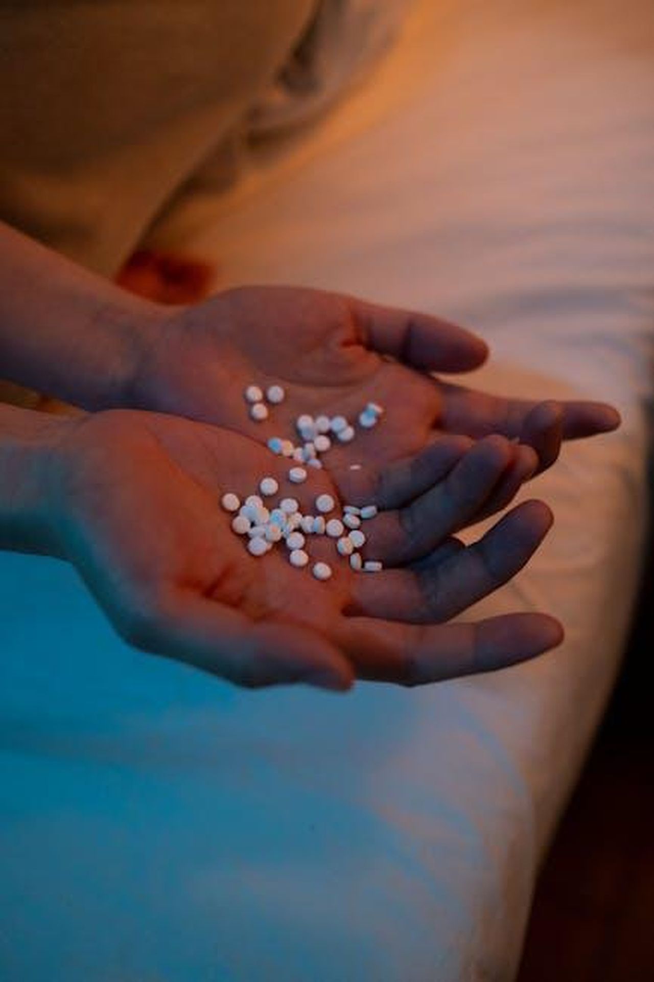 Rick_Springfield_ha_provato_ketamina_e_LSD_per_affrontare_la_depressione_0kEcr2zBFh - Confidenze24 Source: cottonbro studio - pexels - A person holding a handful of pills in a dimly lit bedroom, conveying themes of health and mental wellness.