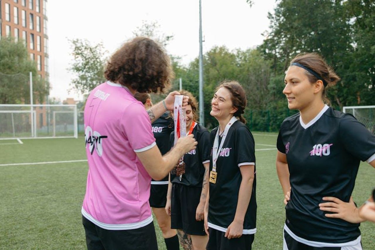 Riconoscimenti_speciali_agli_artisti_qn1jGOY3K2 - Confidenze24 Source: Anastasia Shuraeva - pexels - A women's football team receiving medals on the field, celebrating their victory.