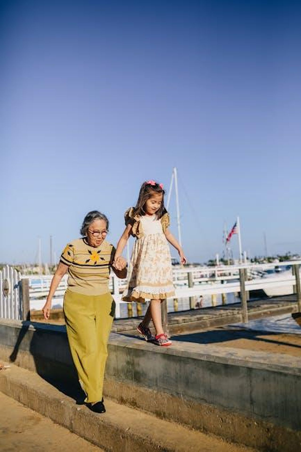Ricordi_del_secondo_appuntamento_di_Jenna_e_Henry_cIN9uVxaMt - Confidenze24 Source: RDNE Stock project - pexels - An elderly woman and a young girl enjoy a sunny day at the marina, holding hands and smiling.