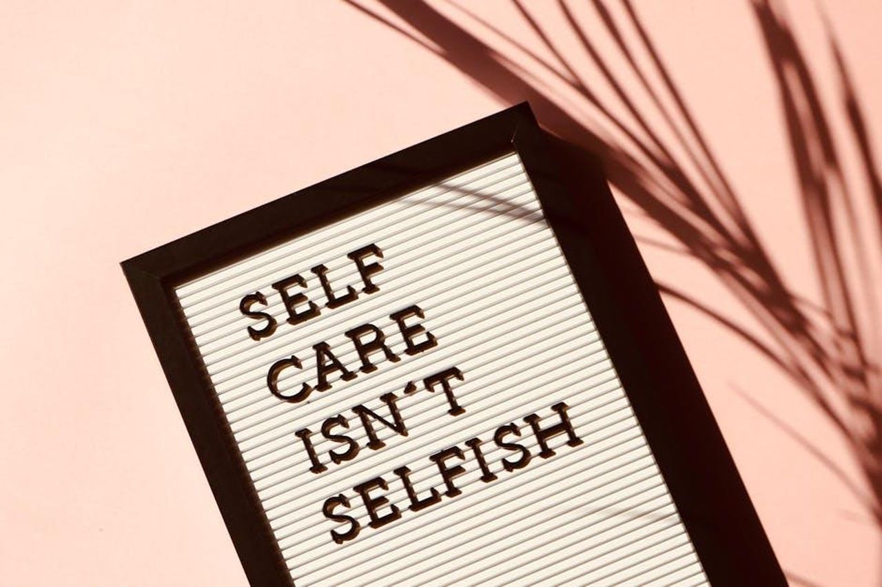 Ricordi_di_Liam_Payne_e_la_sua_lotta_per_la_salute_mentale_5E0WiD1B1Q - Confidenze24 Source: Madison Inouye - pexels - Letter board displaying 'Self Care Isn't Selfish' with artistic shadow on pink background.