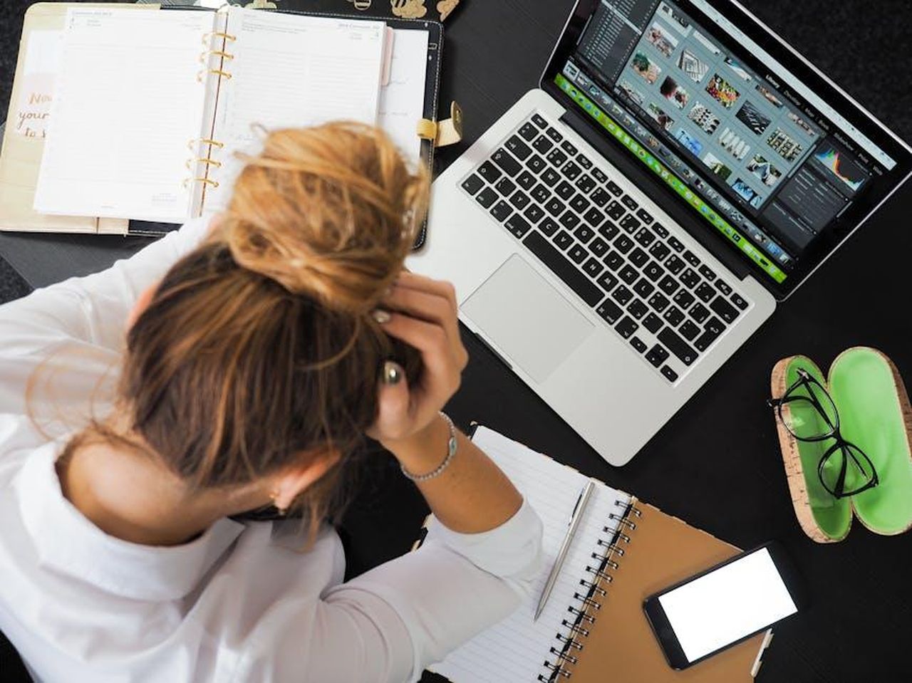 Riduci_lo_Stress_per_Migliorare_il_Benessere_Generale_LS6lfEs2Ka - Confidenze24 Source: energepic.com - pexels - Overhead view of a stressed woman working at a desk with a laptop, phone, and notebooks.