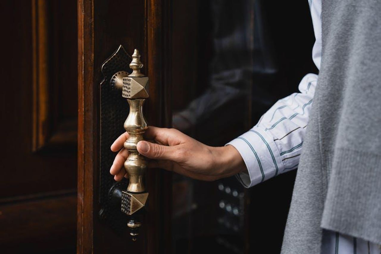 Riflessioni_di_Jenna_sulla_Sicurezza_3vlR6lNTls - Confidenze24 Source: Sueda Dilli - pexels - Close-up of a hand turning an ornate brass door handle, showcasing elegant craftsmanship.