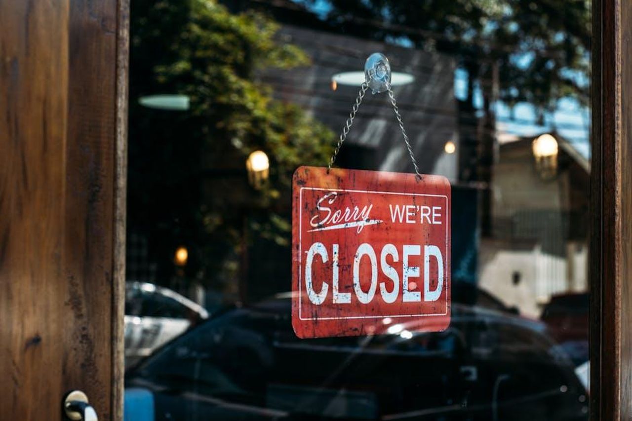Riflessioni_personali_sulla_pandemia_x20oUVVOaA - Confidenze24 Source: Kaique Rocha - pexels - A red closed sign hangs on a glass door, reflecting cars and trees outside.