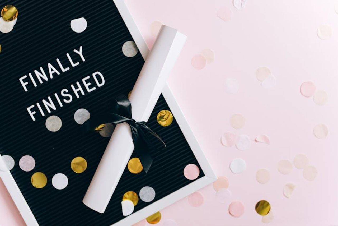 Riflessioni_sulla_finale_di_Sopranos_FVyJgQHGVU - Confidenze24 Source: Leeloo The First - pexels - A graduation scene with a diploma and confetti on a letter board reading 'Finally Finished.'